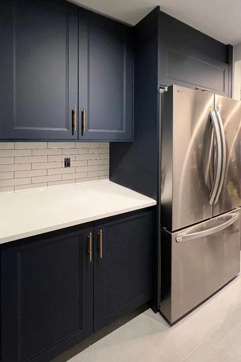 Kitchen corner with navy blue cabinets, white countertop, white subway tile backsplash, and a stainless steel LG refrigerator.