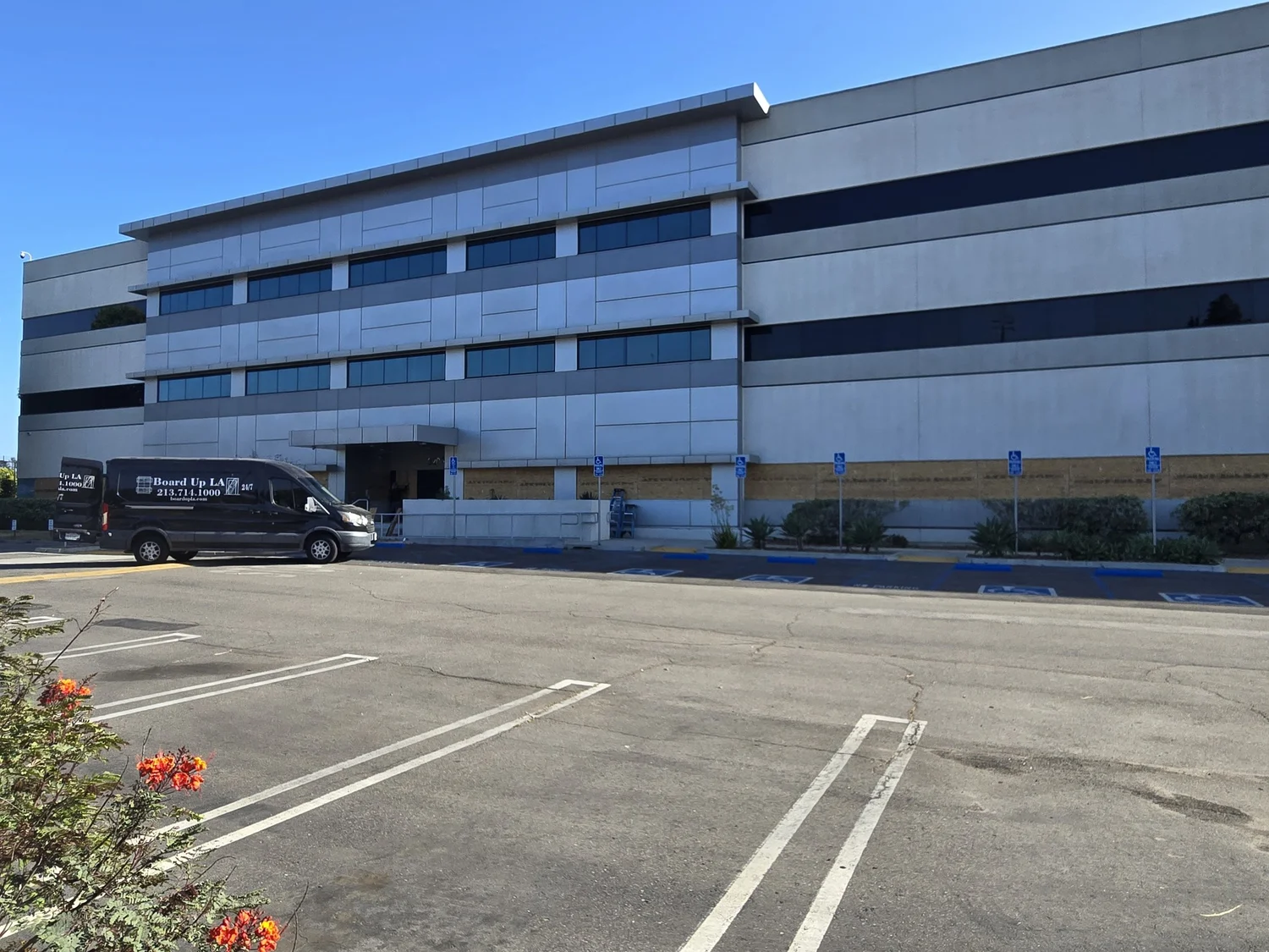 Board Up LA van parked at a commercial building in Los Angeles with the ground-floor windows boarded up with plywood