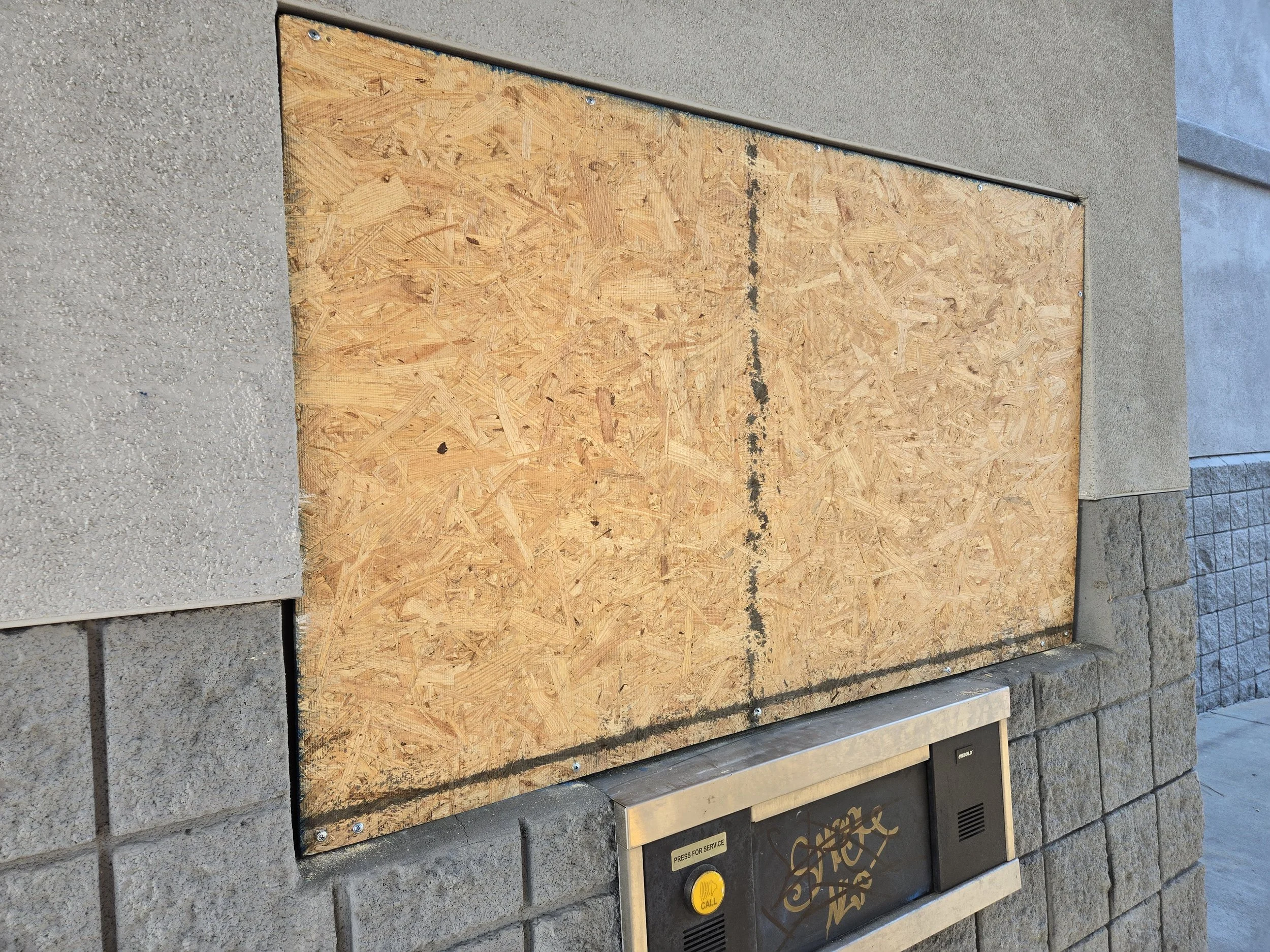 Office building window board-up in Los Angeles — two-panel plywood 
covering a damaged exterior window with precise fit. Commercial 
service by Boardup LA.
