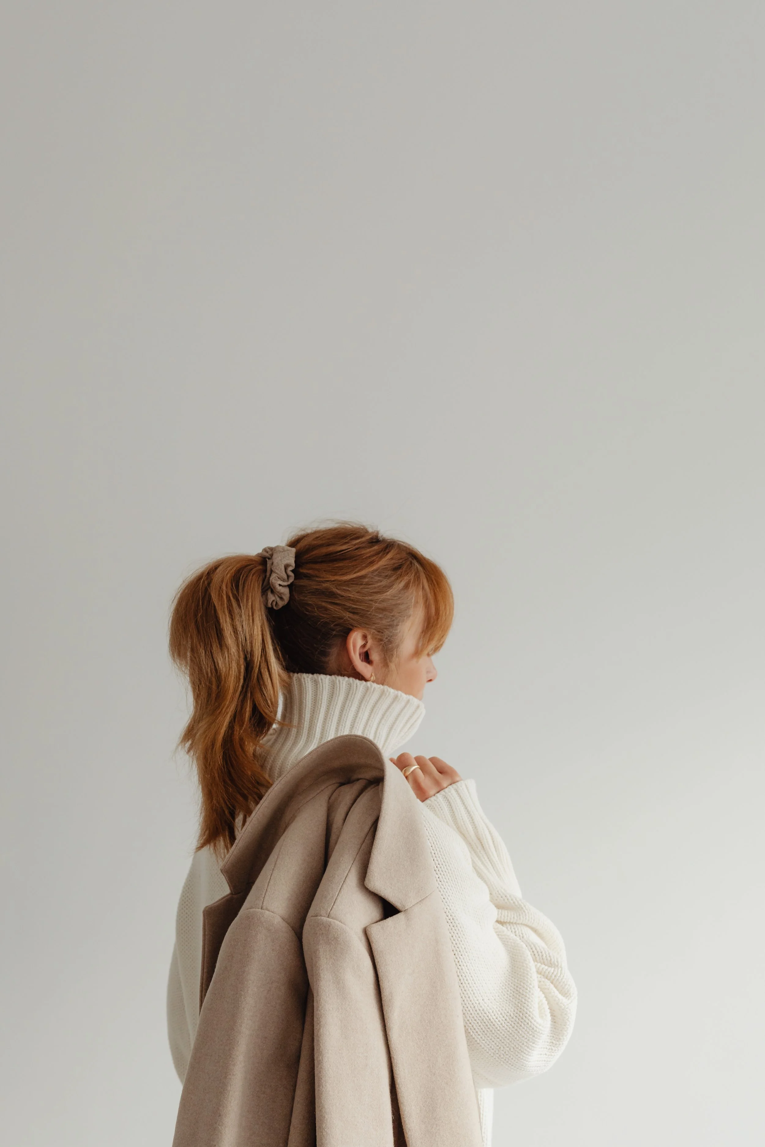Redhead woman looking away from the camera holding her jacket slung over her shoulder