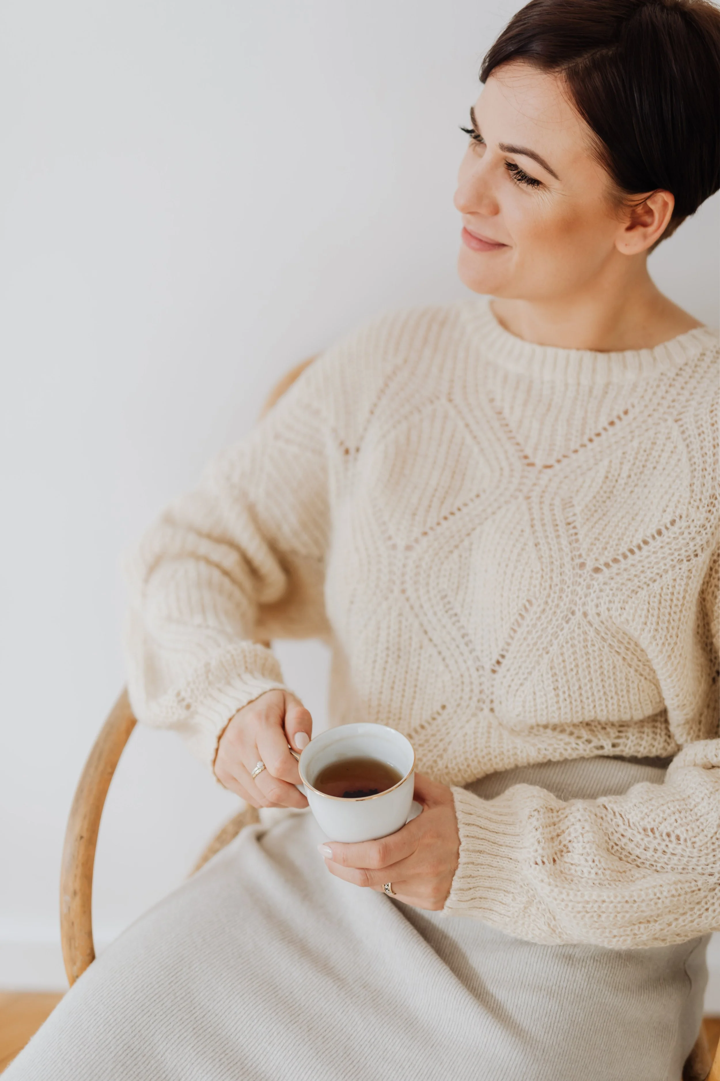 Woman in a white sweater enjoying a cup of coffee