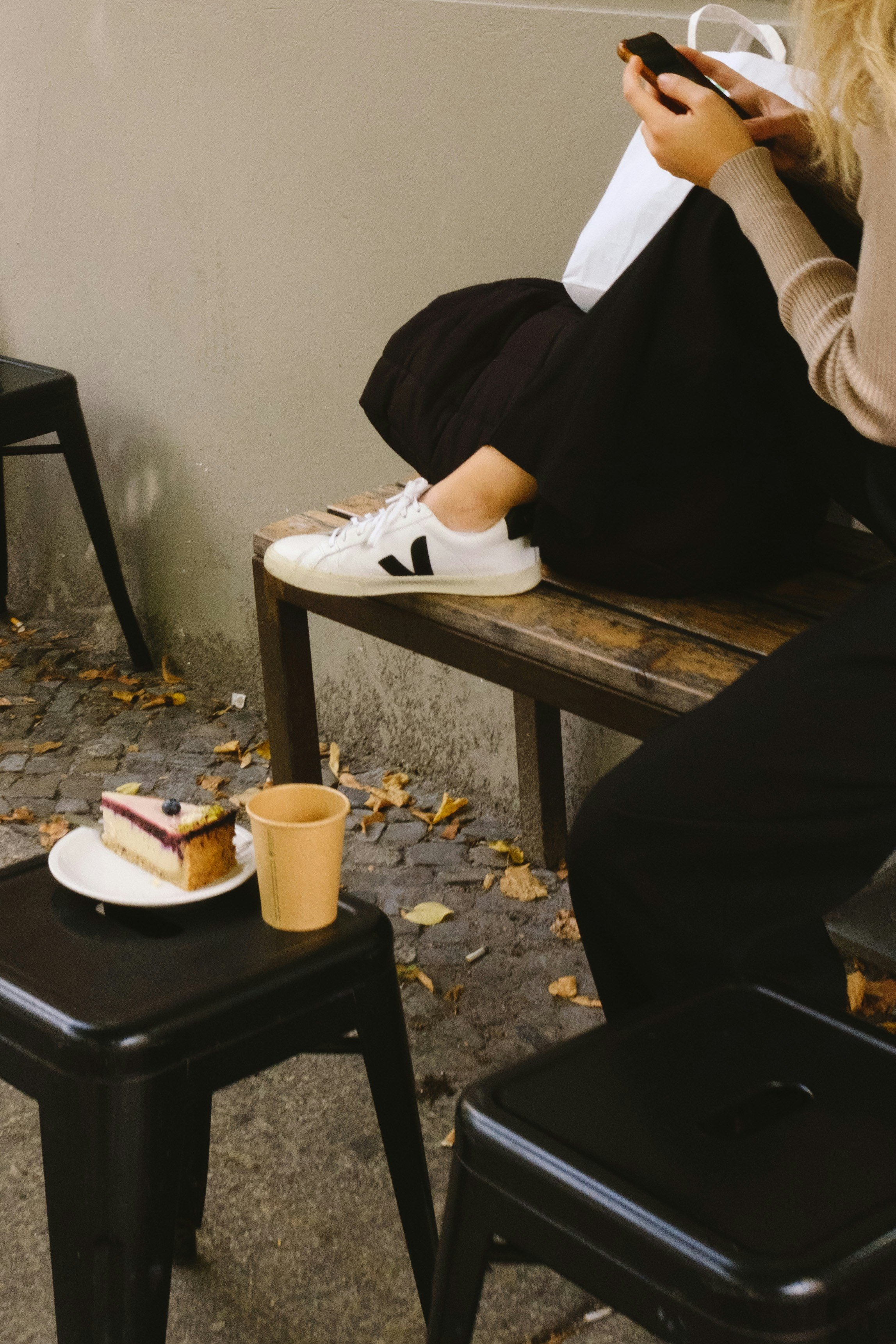 Woman sitting outside on her phone with a coffee and pastry