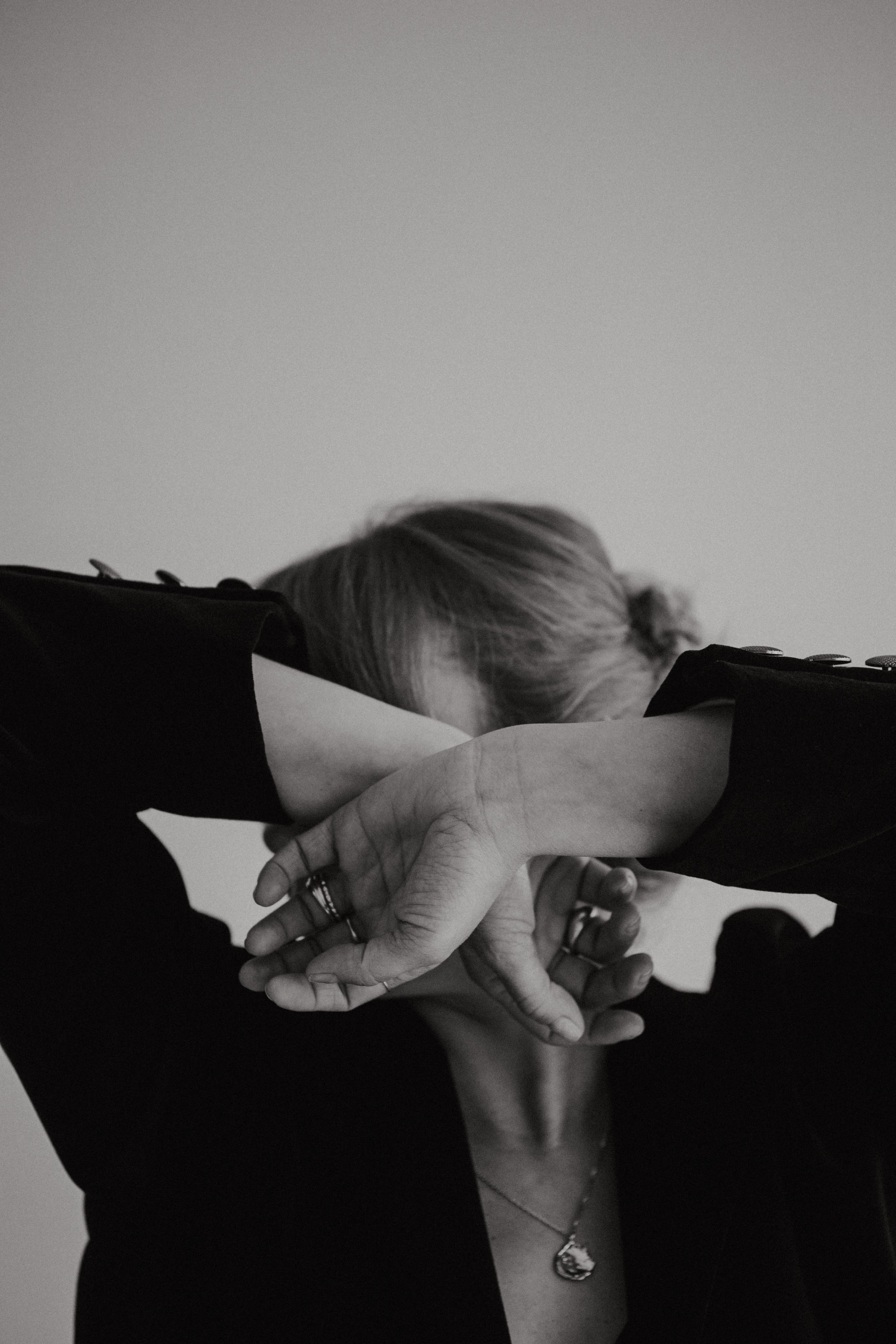 Black and white photo of a woman holding her hands in front of her face with stylish rings and a black shirt