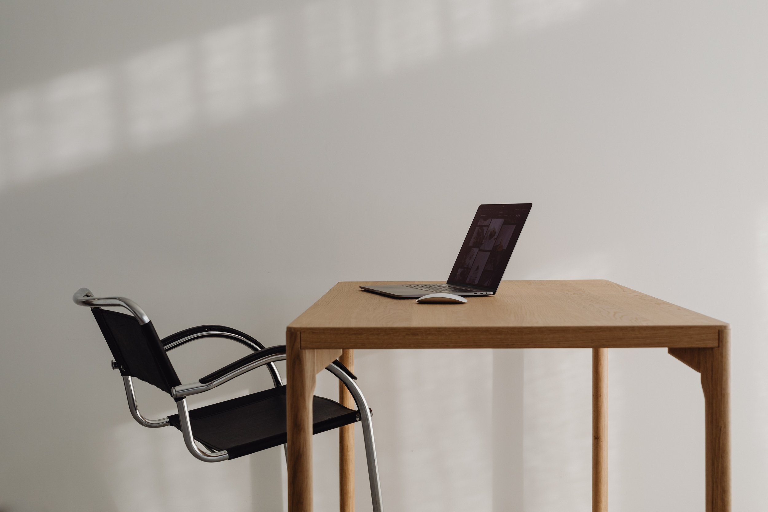 Black desk chair at a warm wood desk and open laoptop