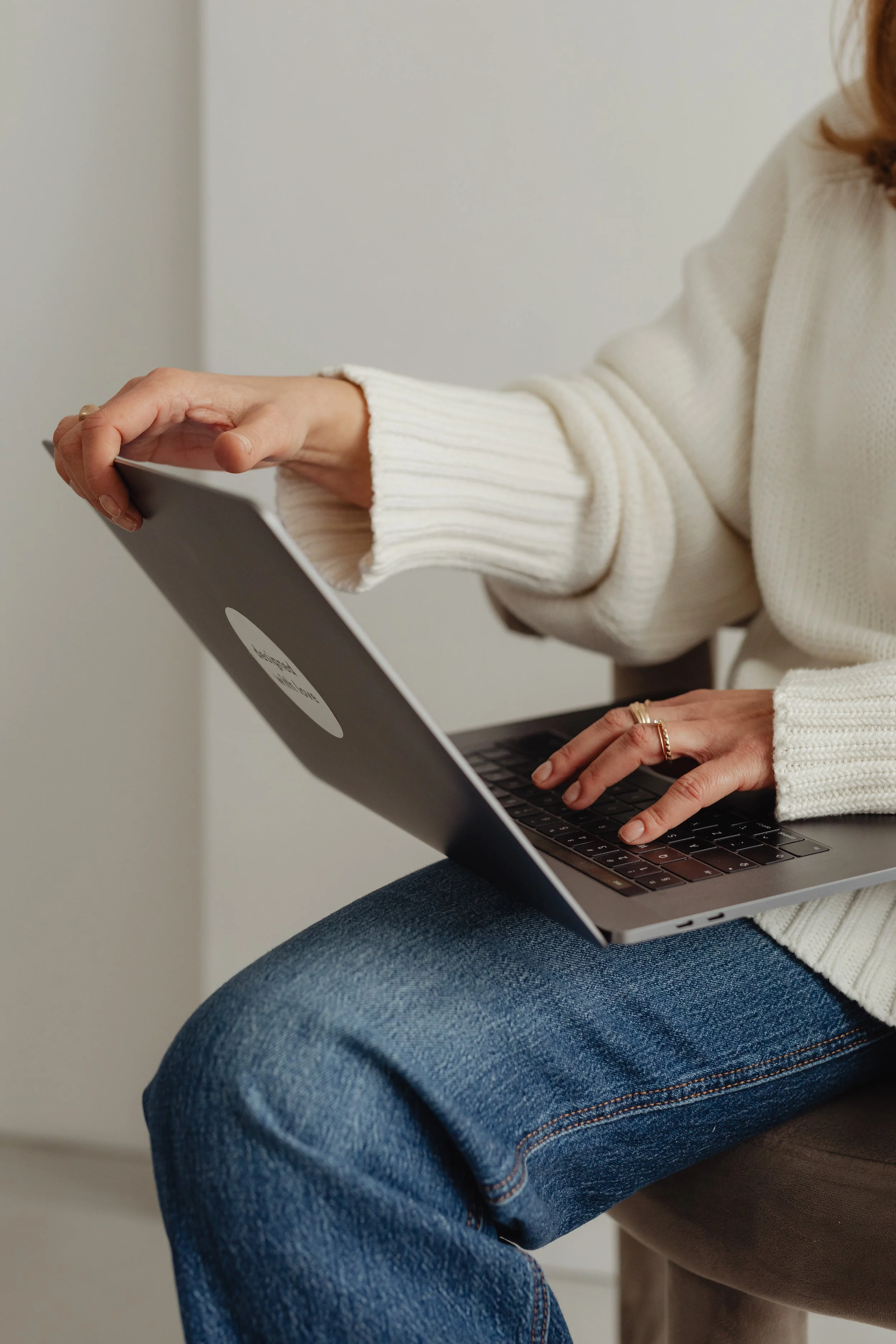Detail of a woan in a white sweater working on her laptop