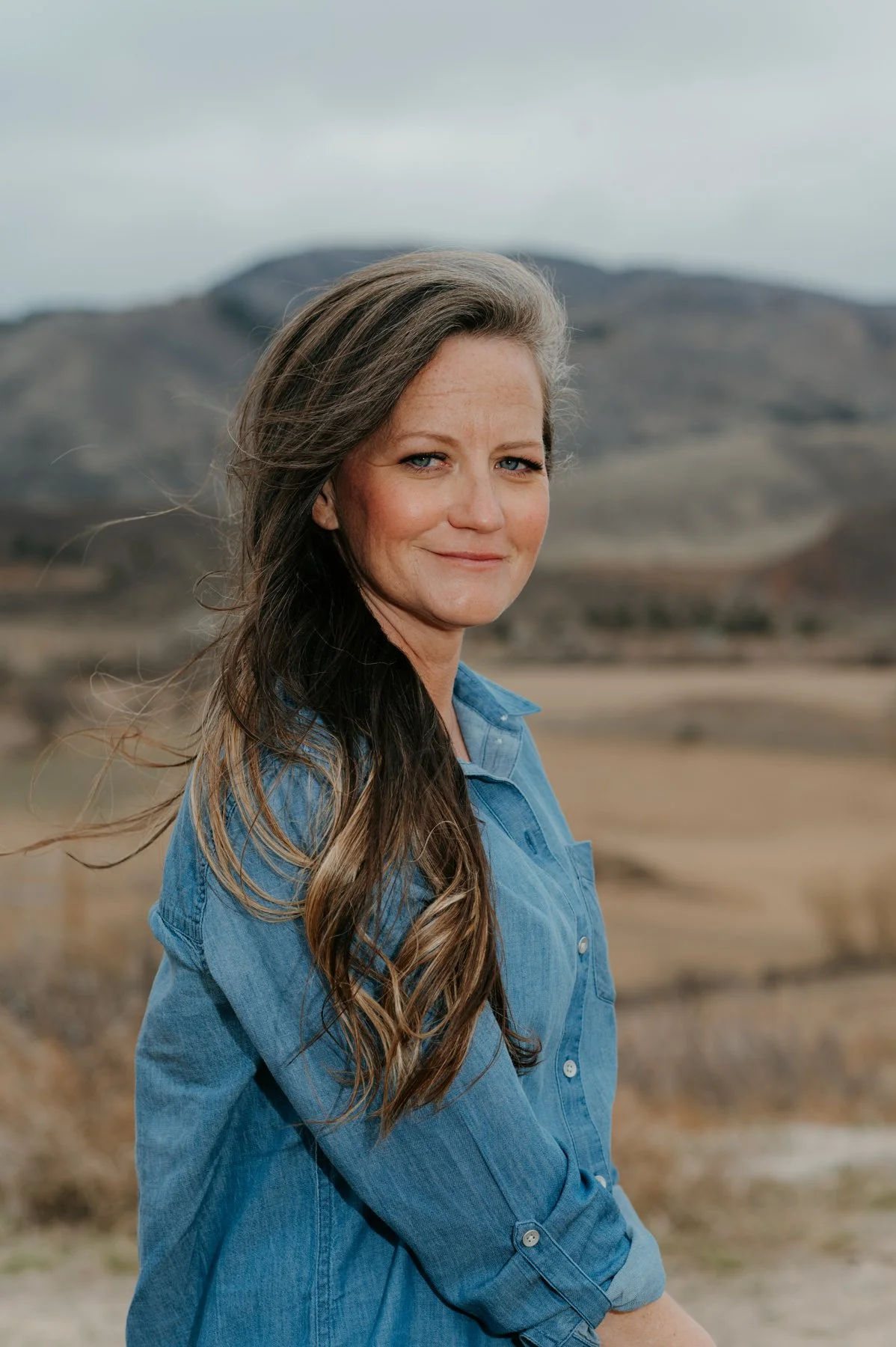 Brie Doyle, Certified Professional Coach and founder of Stellar Perspective Coaching, smiling and standing outdoors in front of a mountain