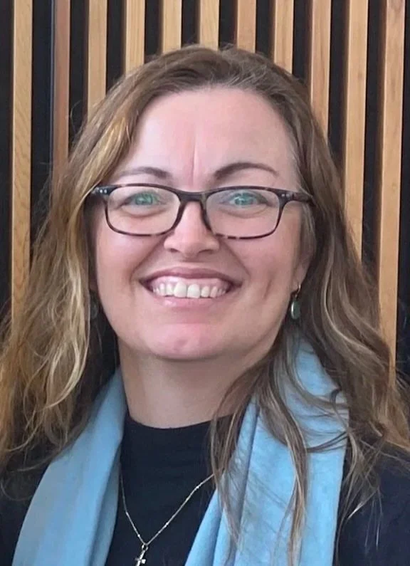 A female counsellor with glasses and long wavy hair smiling.