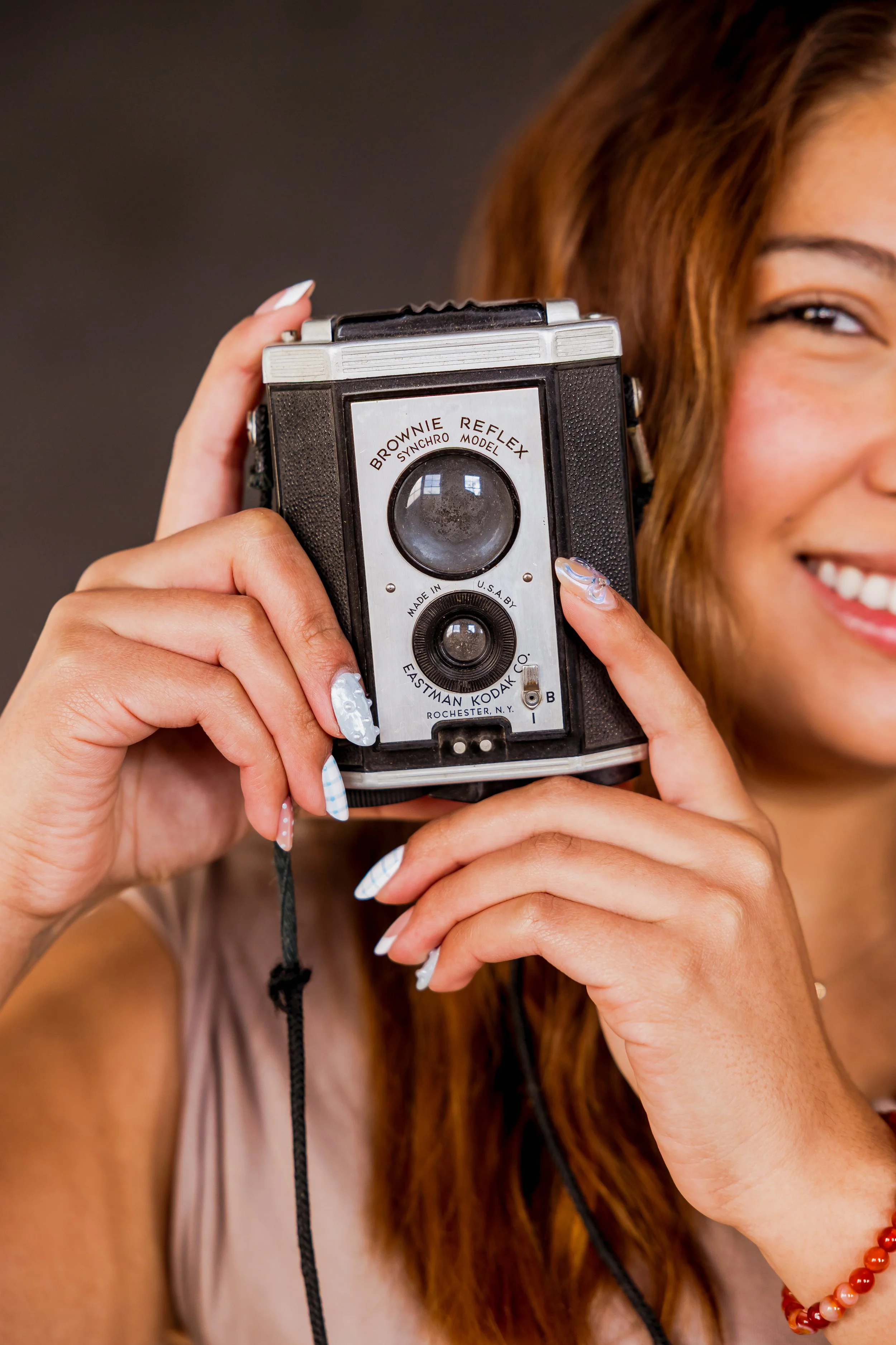 A woman smiling while holding a vintage camera
