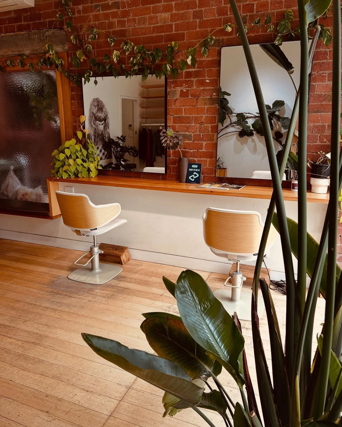 Hair station with two chairs showing hair salon in Fitzroy Melbourne, with brick wall and wooden bench, light, open, and inviting