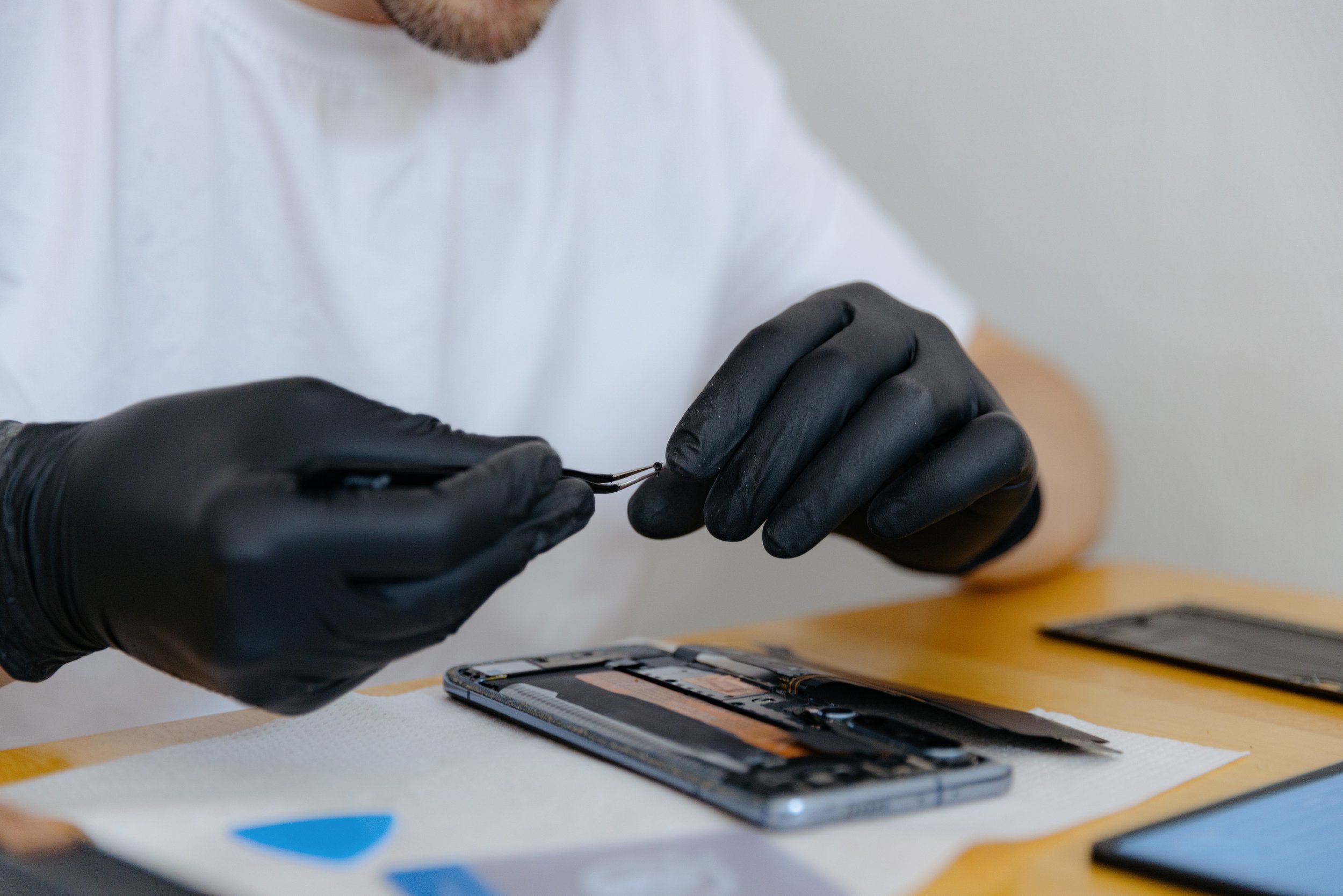 Person wearing black gloves arranging makeup palettes and brushes on a table.