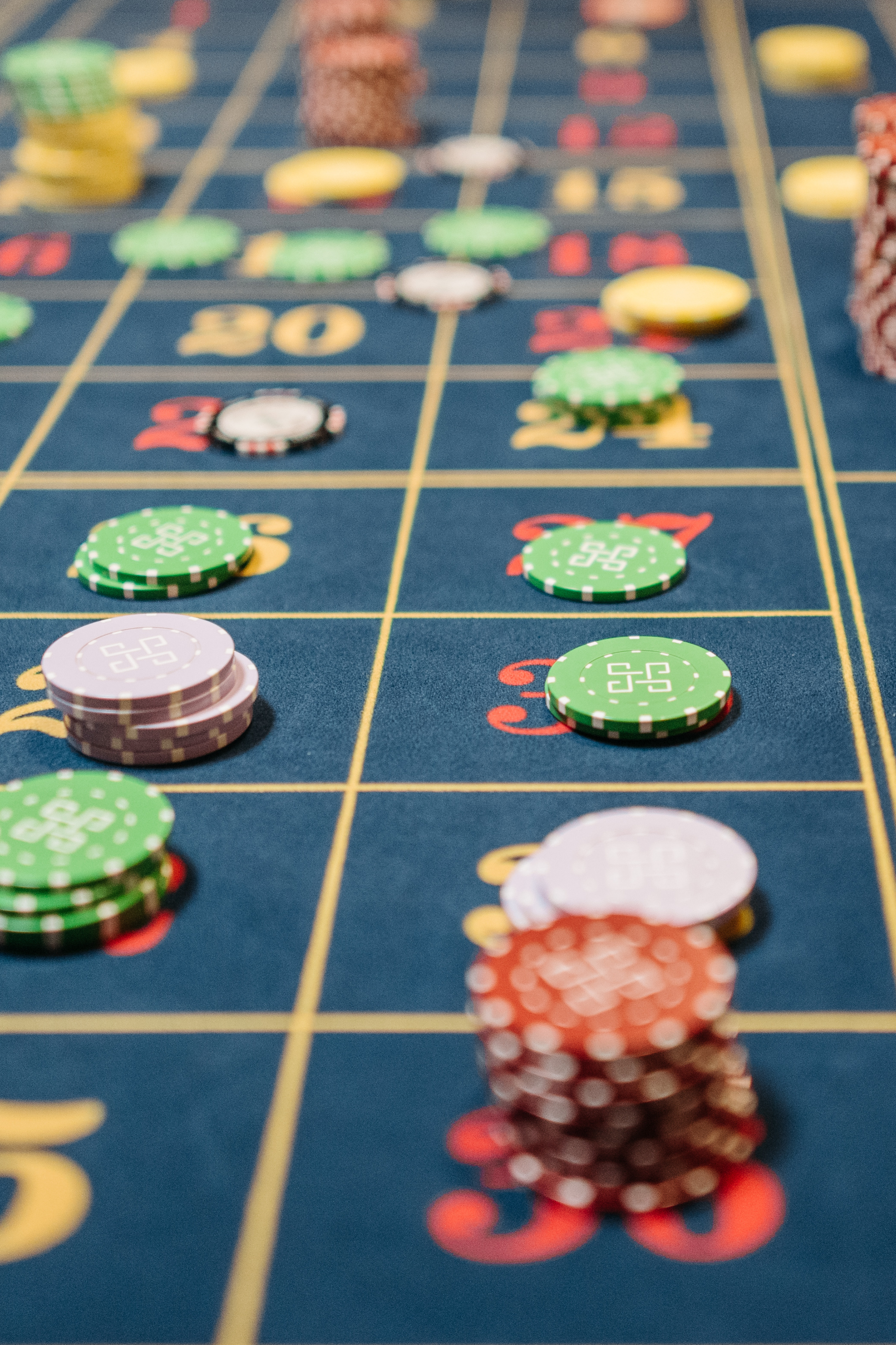 Close-up of a roulette table with stacks of chips placed on various numbers and betting areas.