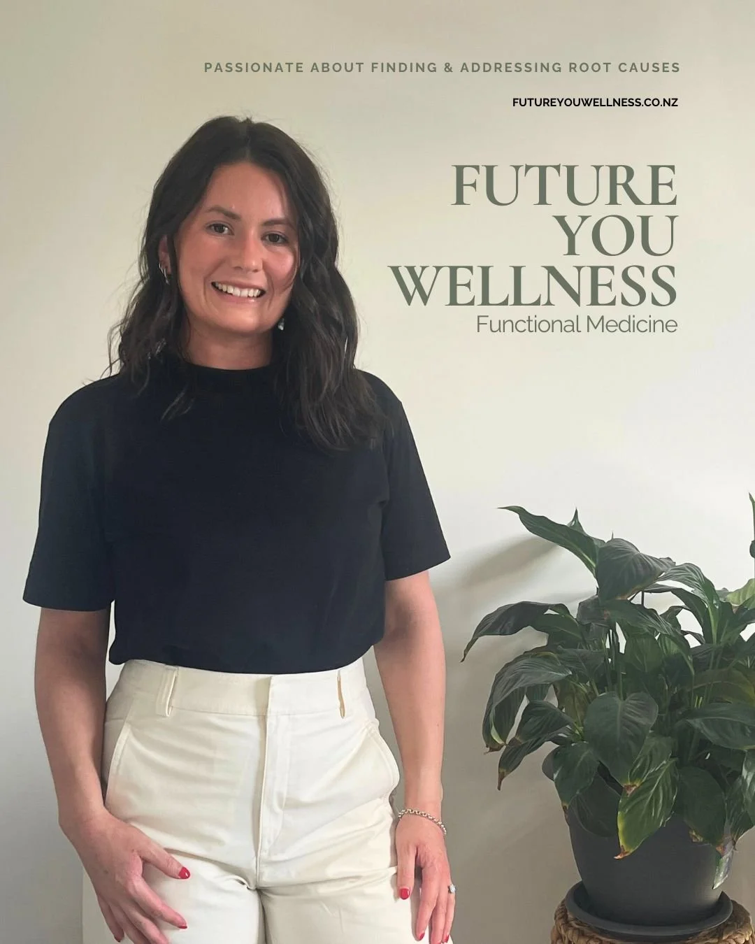 A woman with dark wavy hair smiling, wearing a black top and cream-colored pants, standing next to a large leafy green plant and a wall with text promoting wellness and functional medicine.