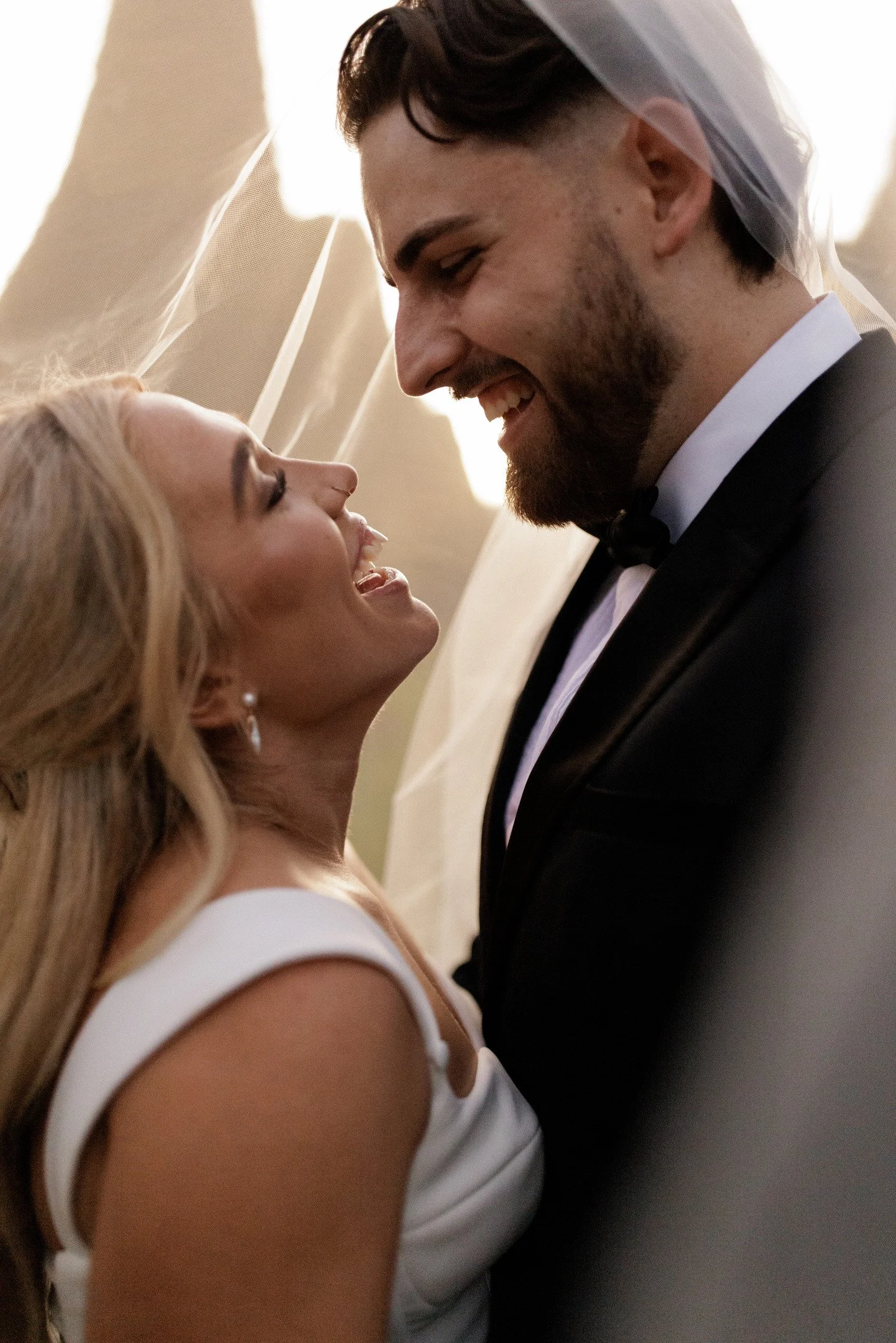 A bride and groom smiling and looking at each other during their wedding ceremony.