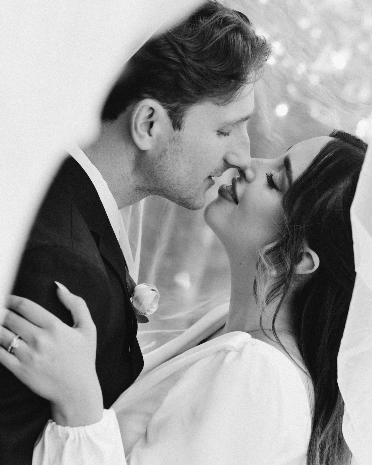Black and white photo of a bride and groom with their faces close, about to kiss, with tender expressions.