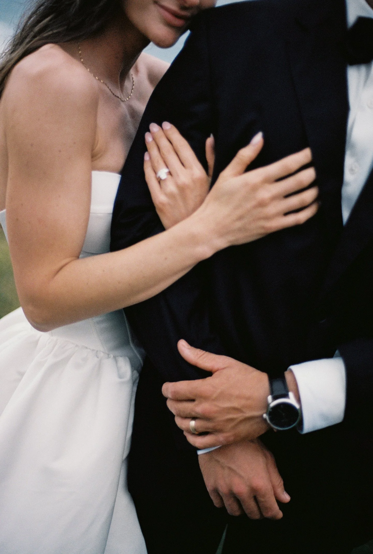 A woman in a wedding dress and a man in a suit embrace closely, showing affection and intimacy.