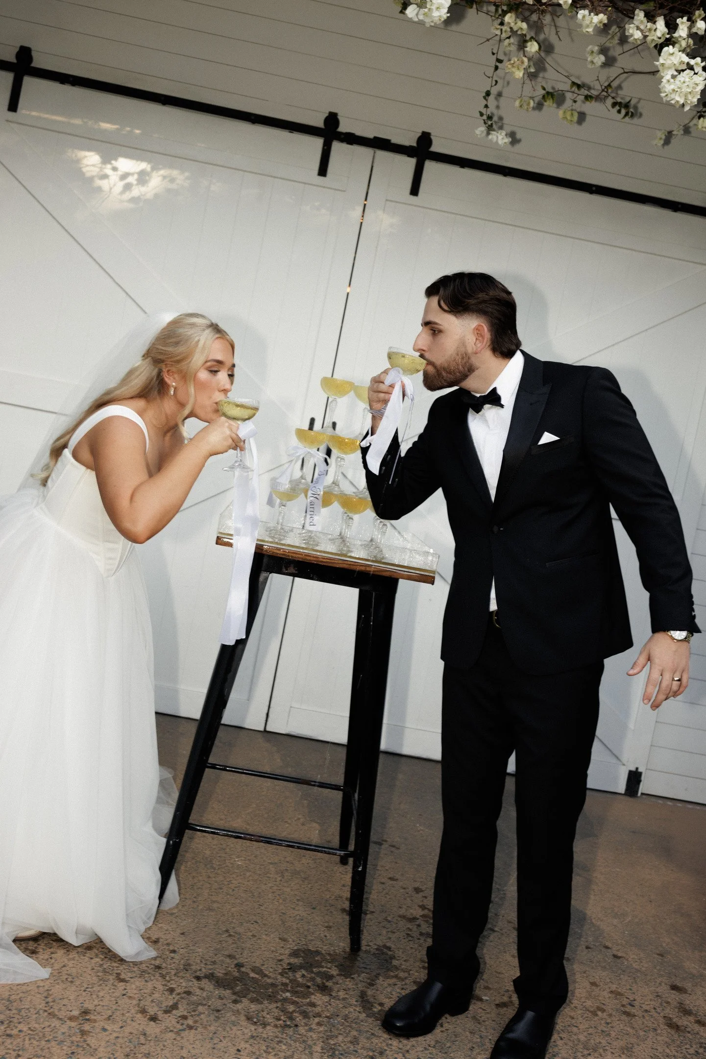 Bride and groom in formal attire sharing a toast with lemonade drinks in coupe glasses at their wedding reception.