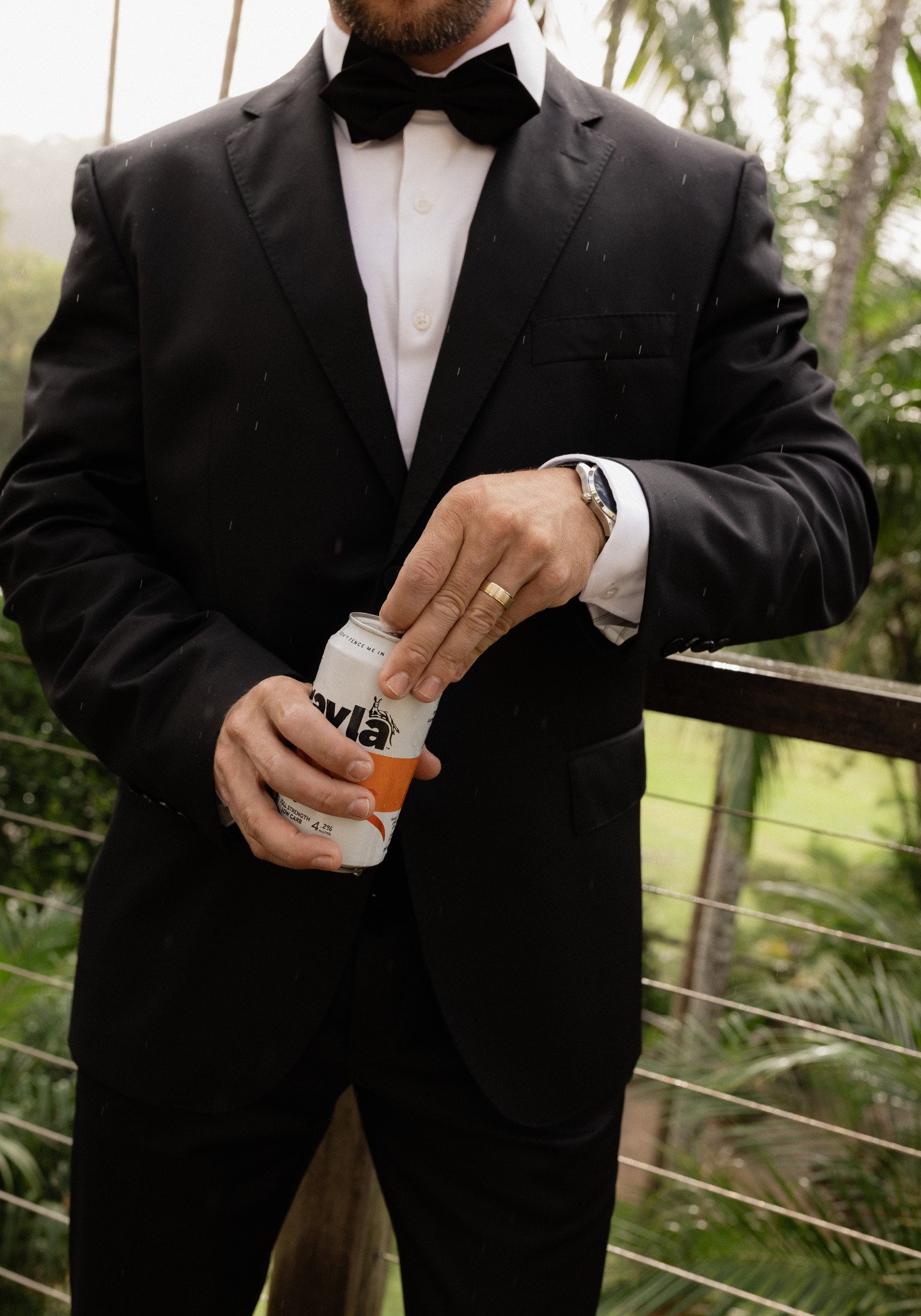 Man in a tuxedo and bow tie opening a can with a logo that reads 'Viva'.