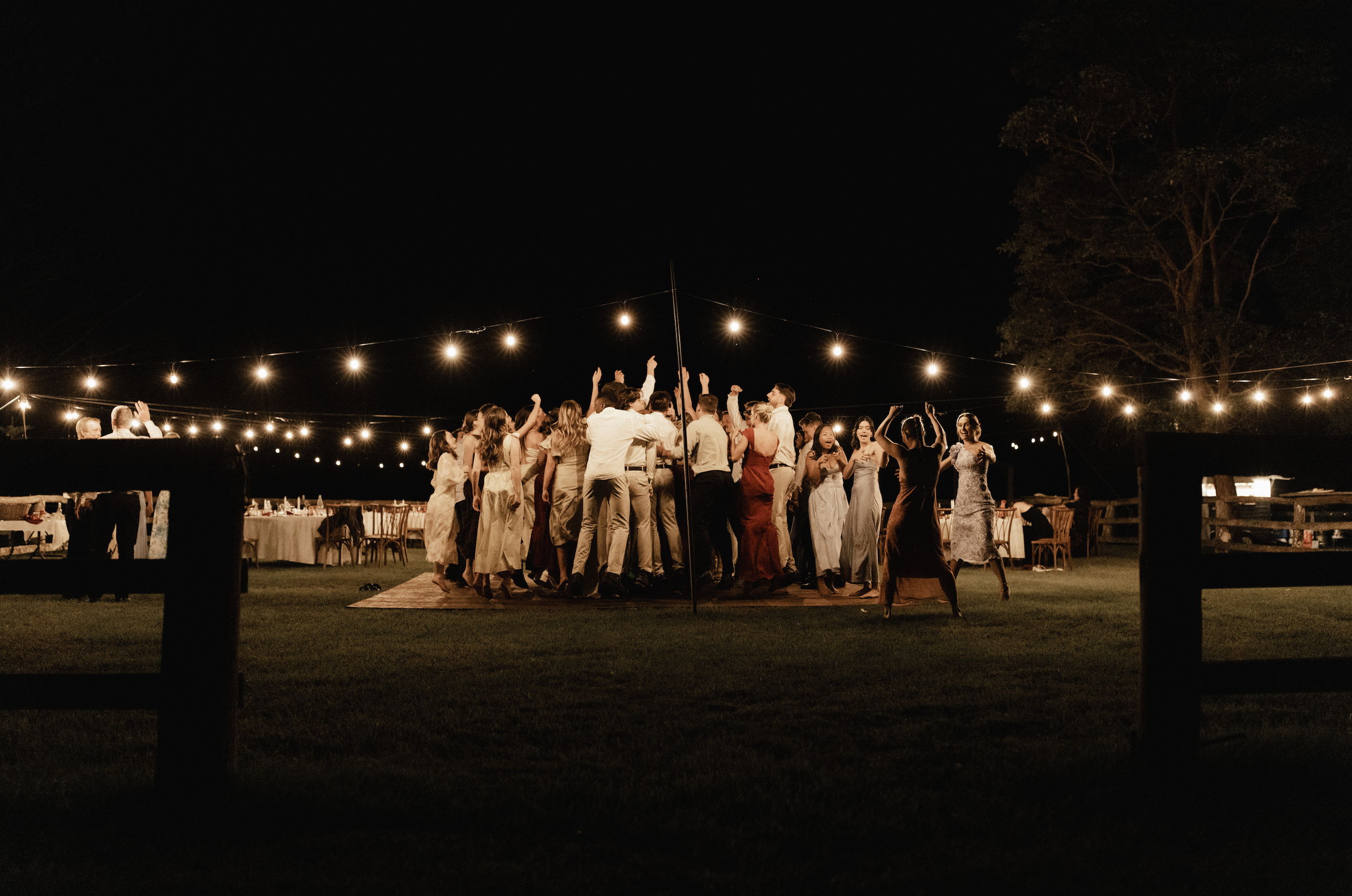 People dancing at an outdoor night celebration under string lights