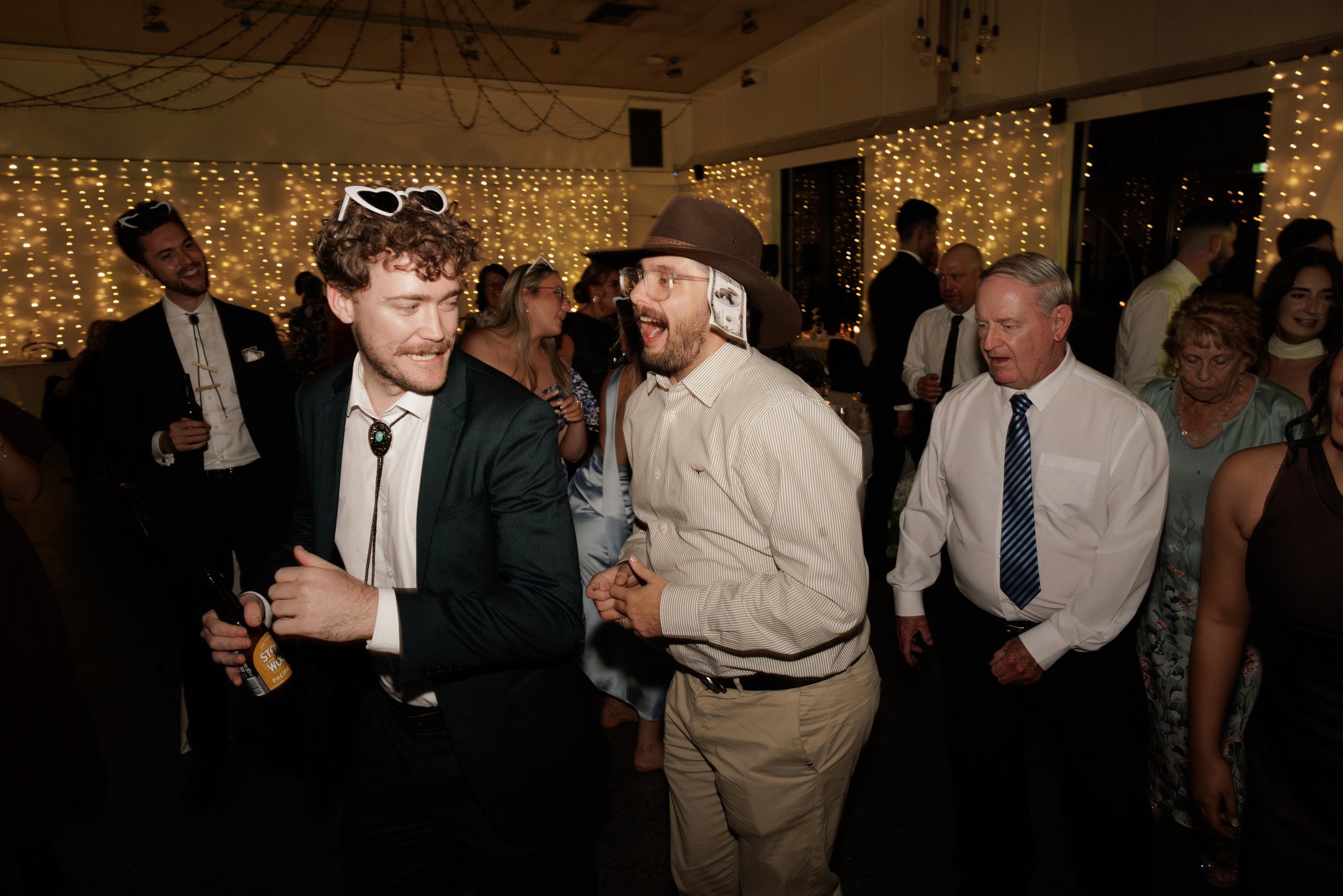 People dancing and socializing at a party or celebration with string lights and dark atmosphere.