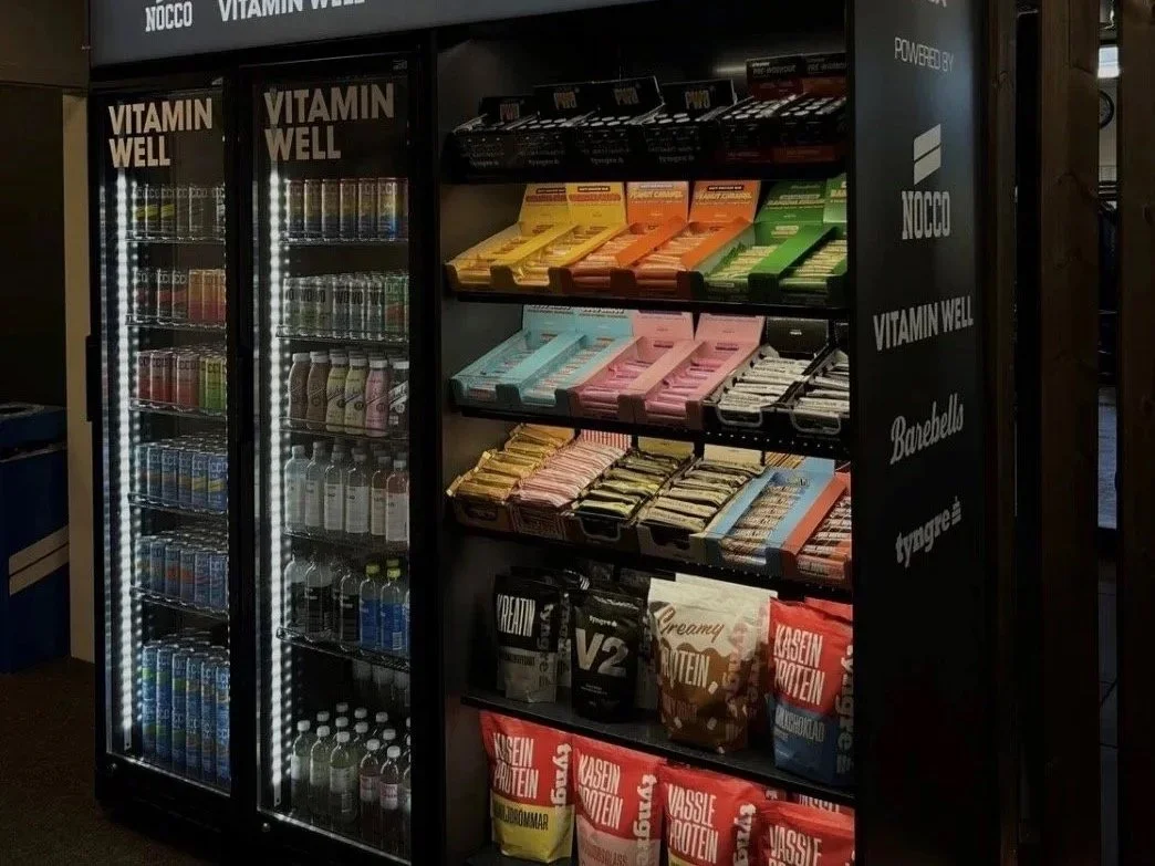 Exponeringskyl med drycker, snacks och proteinprodukter på gym och träningsanläggning.