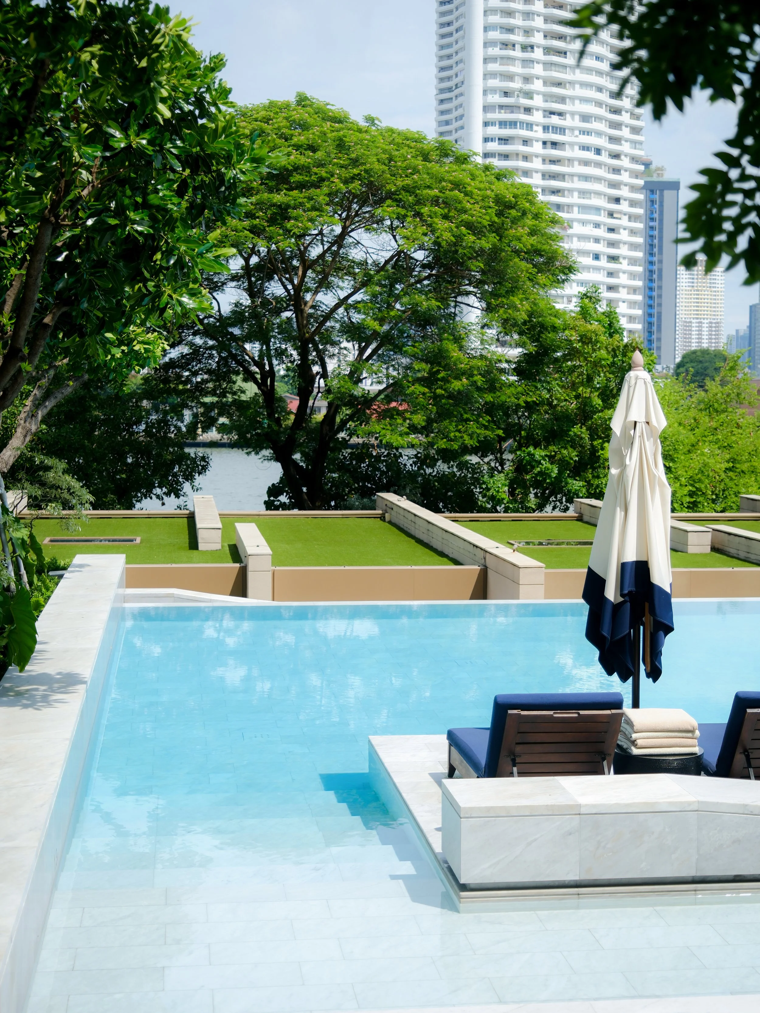 Capella Bangkok infinity pool with Bangkok city skyline and white parasols — luxury hotel photography by Dillon Atsiil
