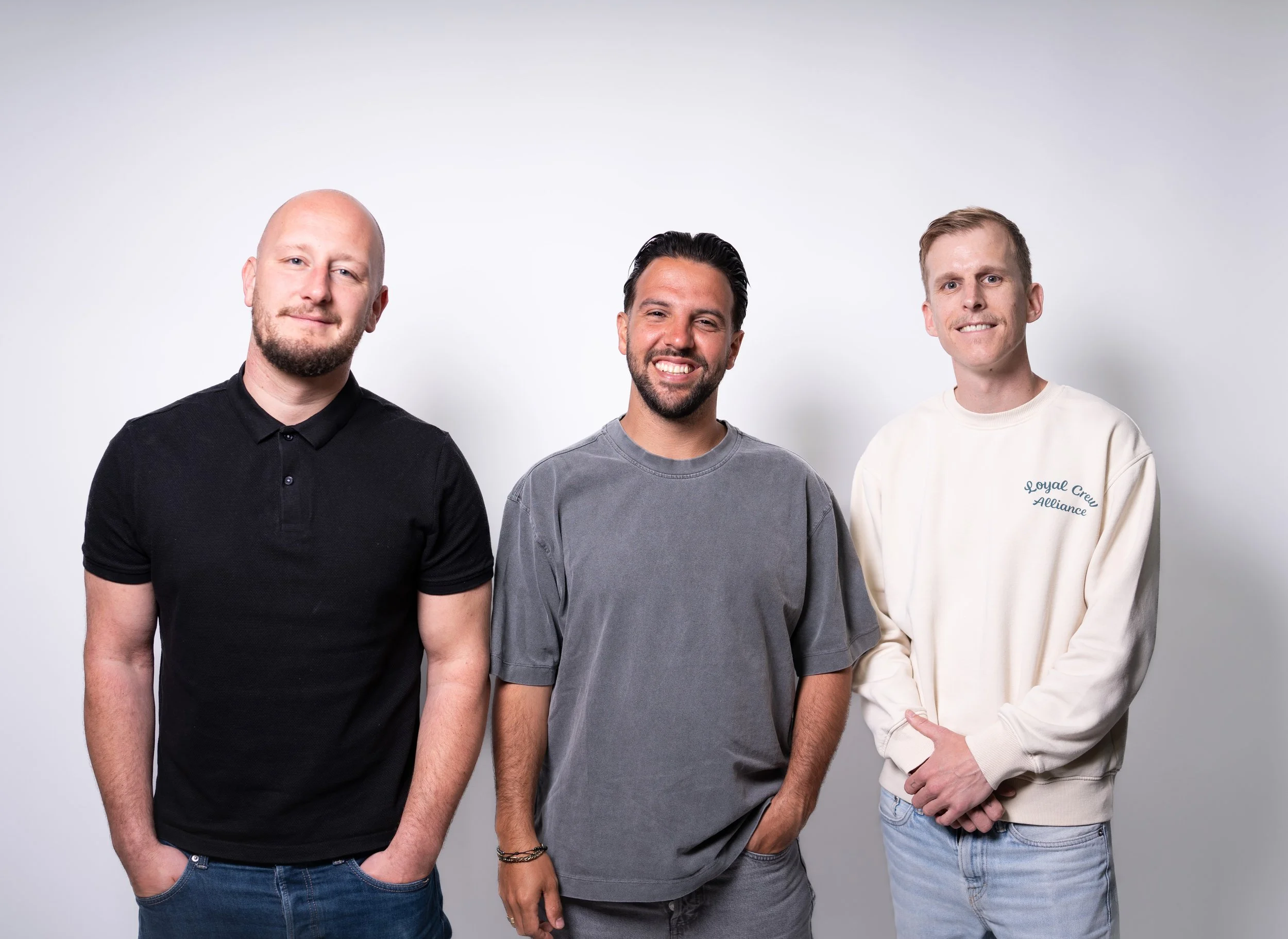 de oprichters van podcast studio westland: Dave Laarman, Brahim Mohcin en Dave van den Berg kijken lachend naar de camera in de studio van podcast studio westland