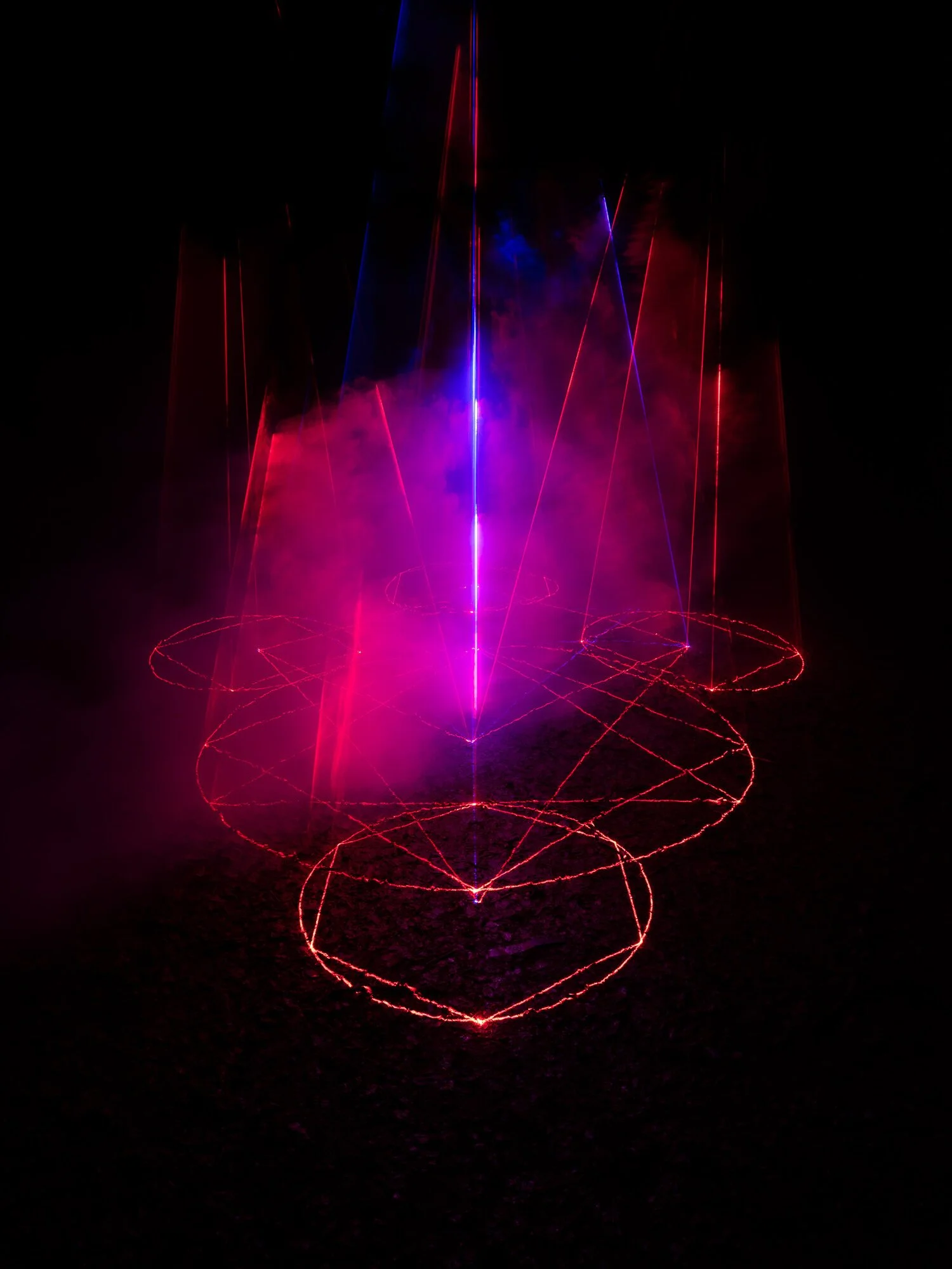 Cathedral of Ego: Light, Code, and Transcendence  MAXIME PLESCIA-BÜSCHI AND BJØRN STAAL  x COLLECTIVE OSLO Laser light show with red and purple beams creating circular patterns and purple fog in darkness.