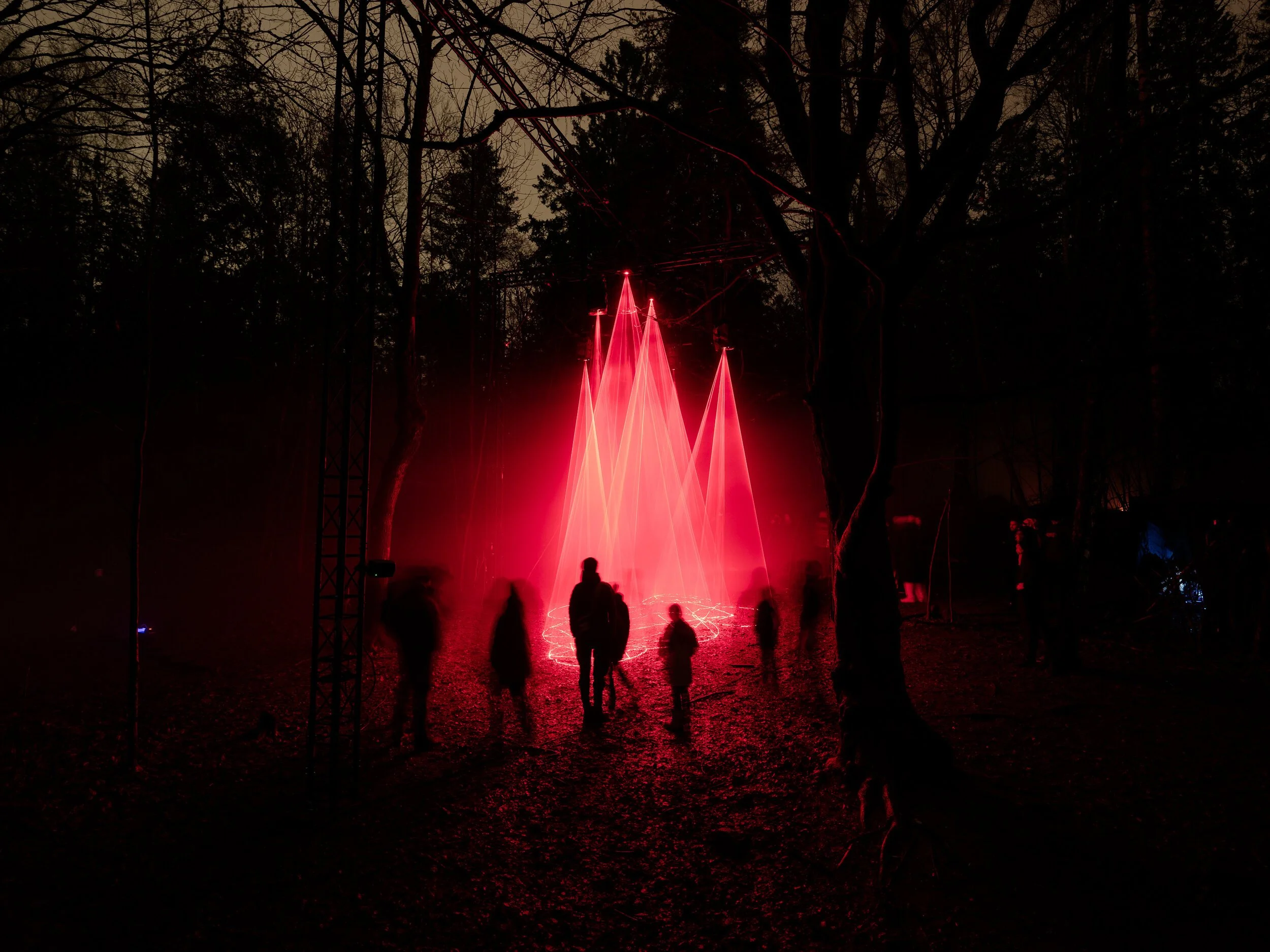 Cathedral of Ego: Light, Code, and Transcendence  MAXIME PLESCIA-BÜSCHI AND BJØRN STAAL  x COLLECTIVE OSLO People walking through a forest illuminated by red laser lights and fog.