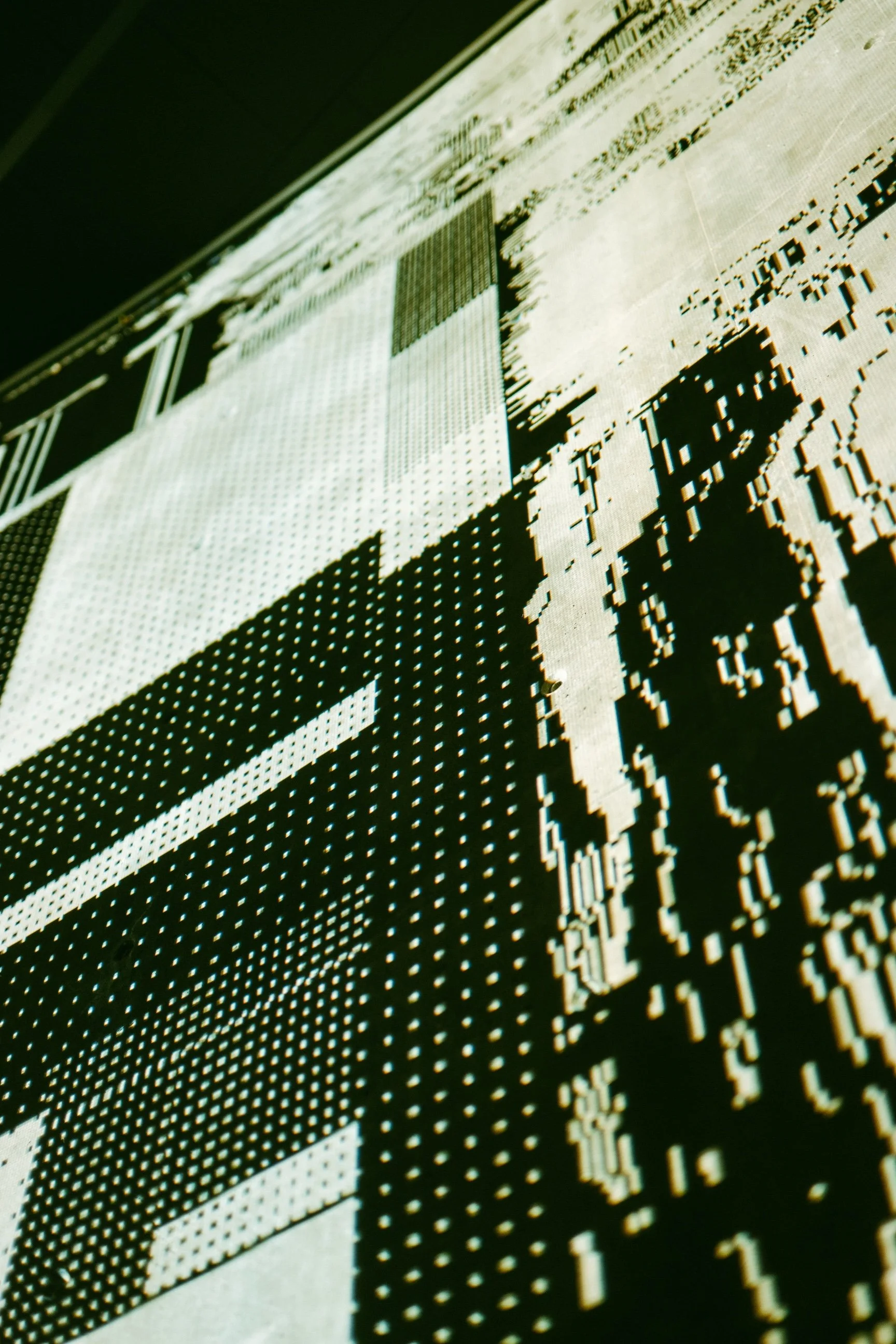 Close-up view of a digital stock market screen displaying stock prices, graphs, and numerical data in green and white on a black background.