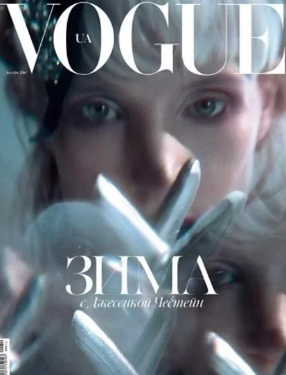 Close-up of a woman's face with blue eyes, wearing white gloves, on the cover of Vogue magazine with the title in large letters.