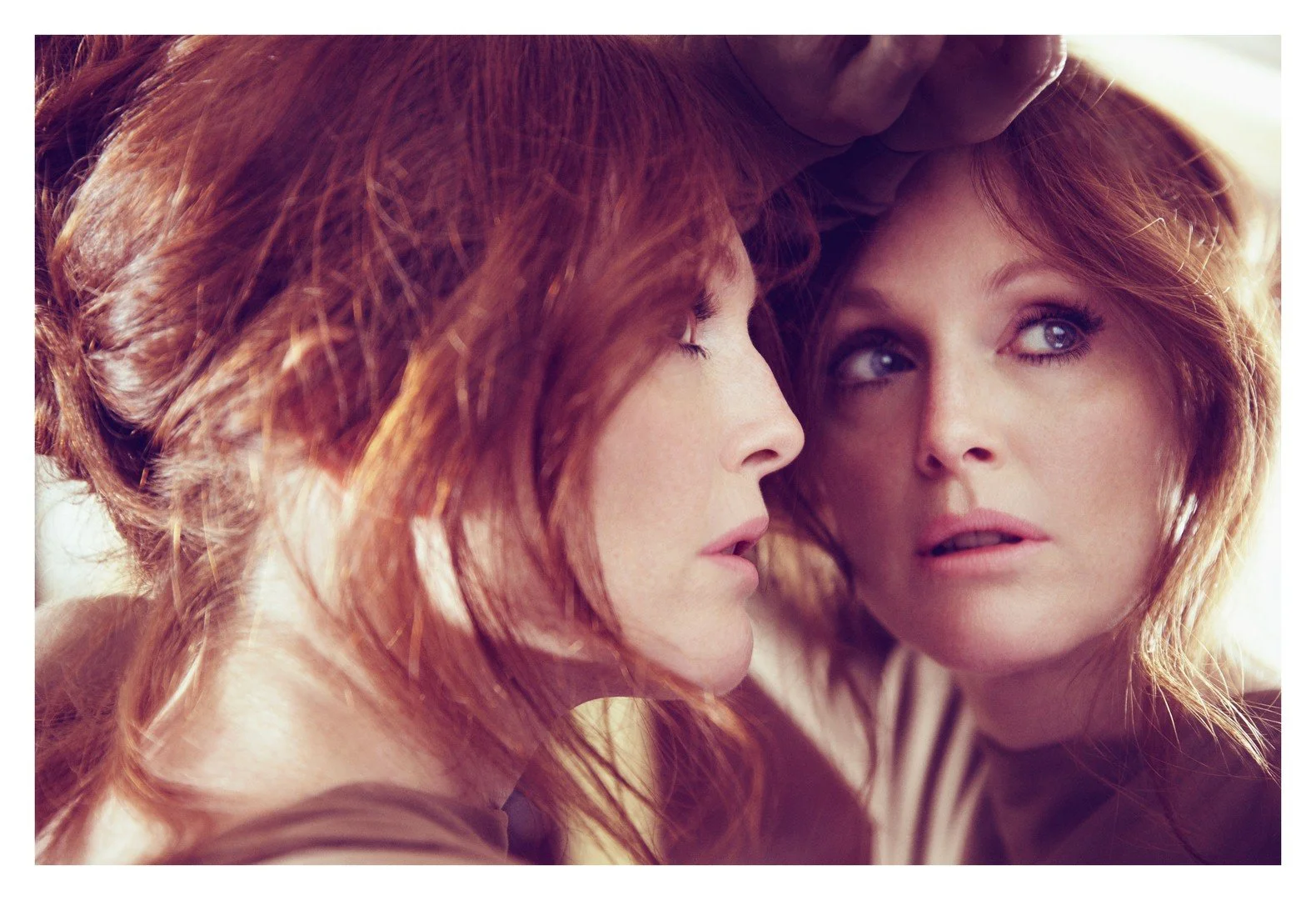 Two women with red hair close together, one with her eyes closed and the other looking pensively to the side, sharing an intimate moment.