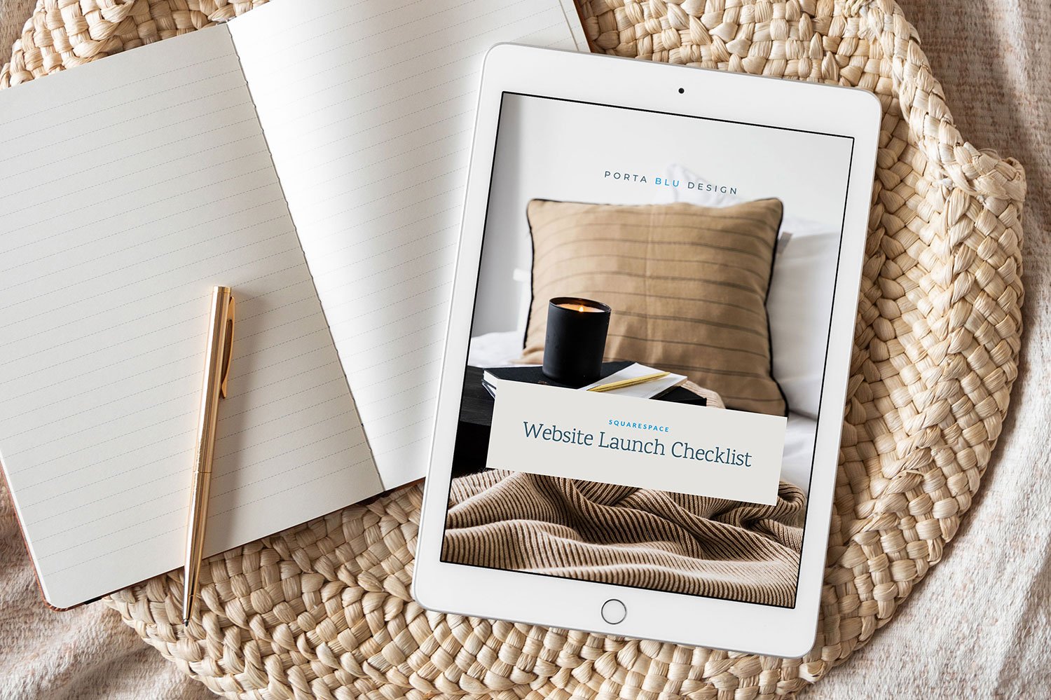 Tablet displaying a website launch checklist, next to a notebook and gold pen on a woven placemat.