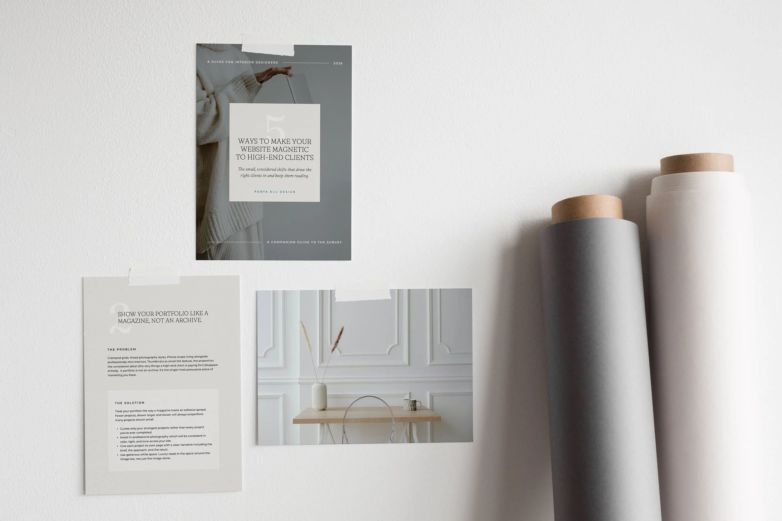 Wall with printed articles and a poster about interior design. Three cylindrical vases on a table and decorative molding on the wall.