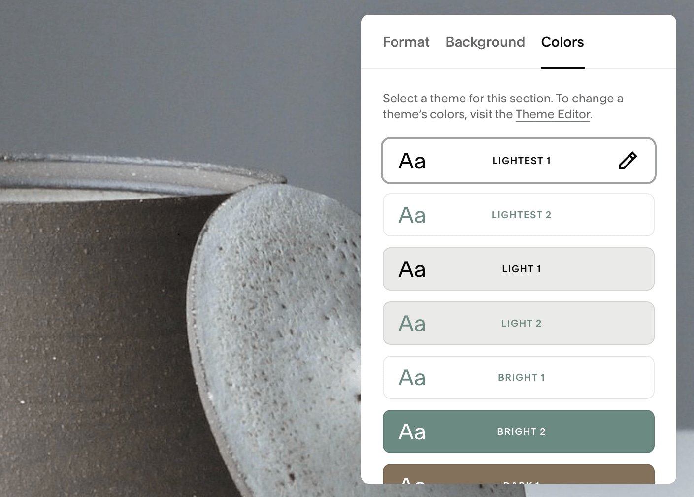 A color theme selection menu is open on a digital interface, overlapping a close-up of two ceramics with earthy tones.