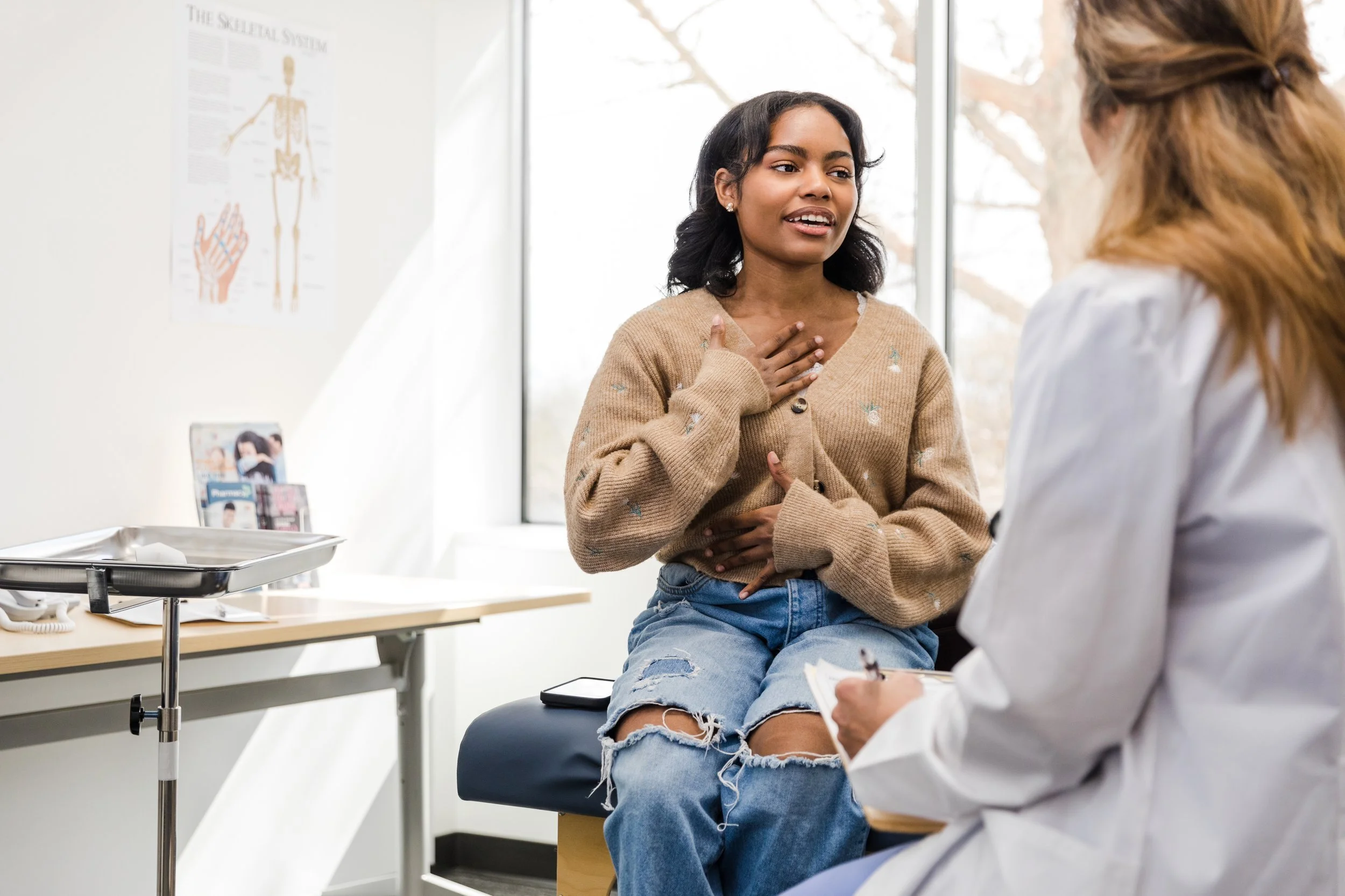 woman discusses her health with a doctor while seated in a chair during a consultation