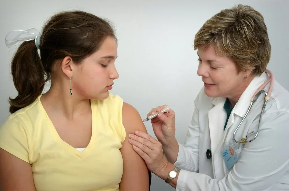 Pediatric nurse giving vaccination shot to a child