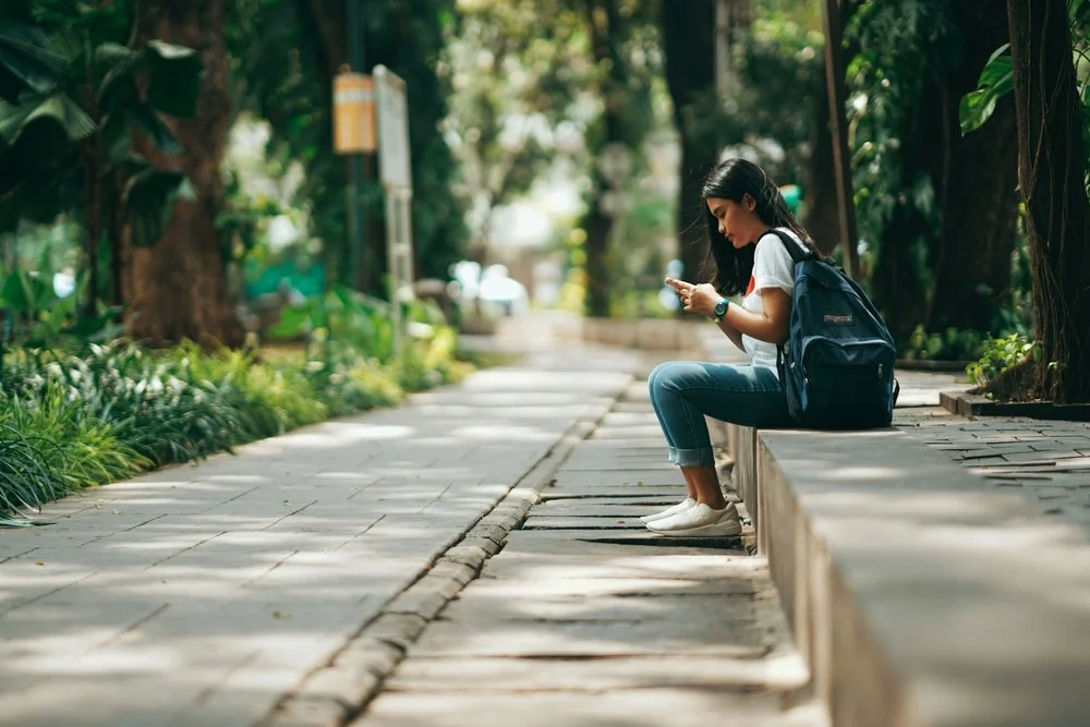 Teen on phone sitting on park bench