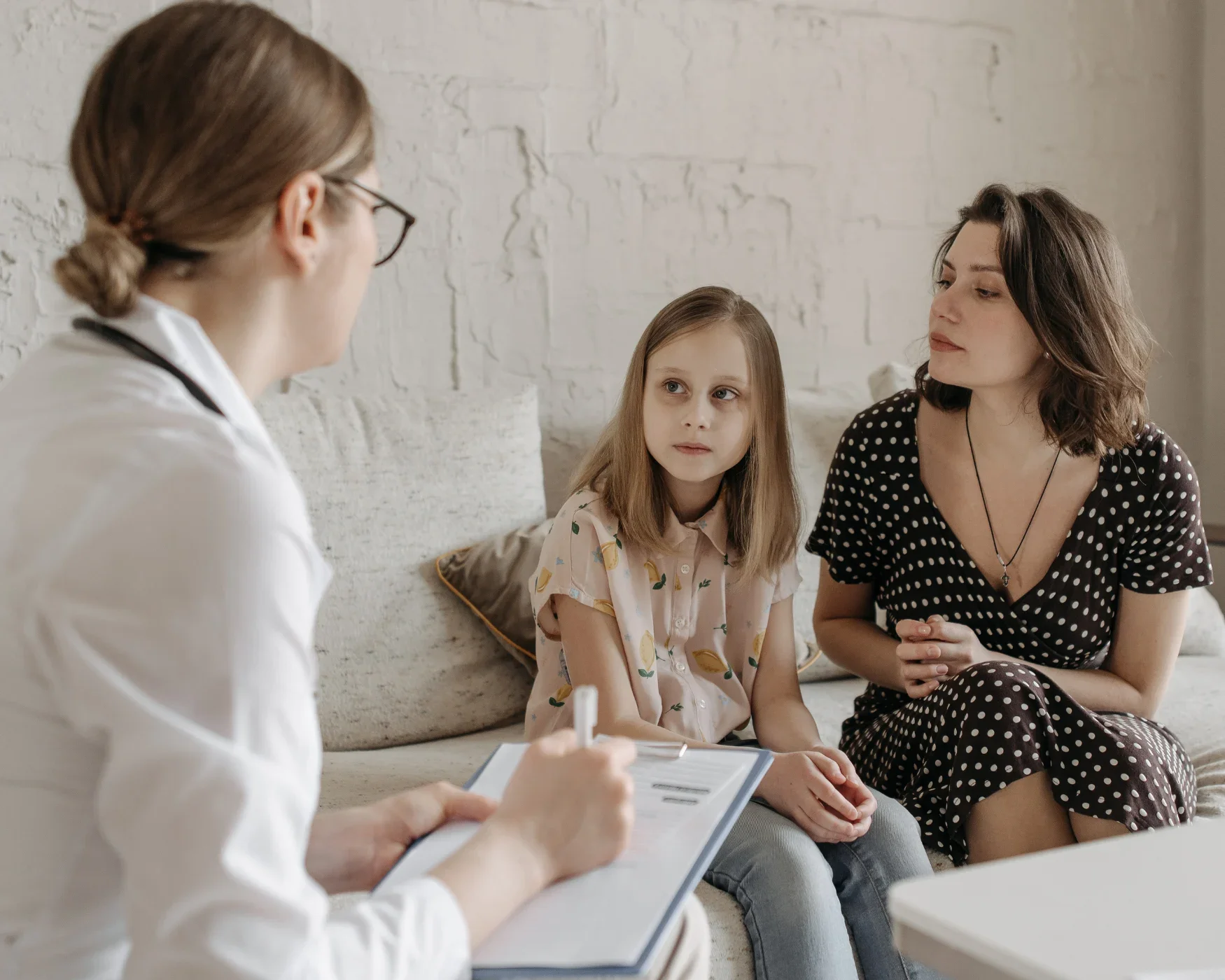 Pediatrician with clipboard speaking with child and mother