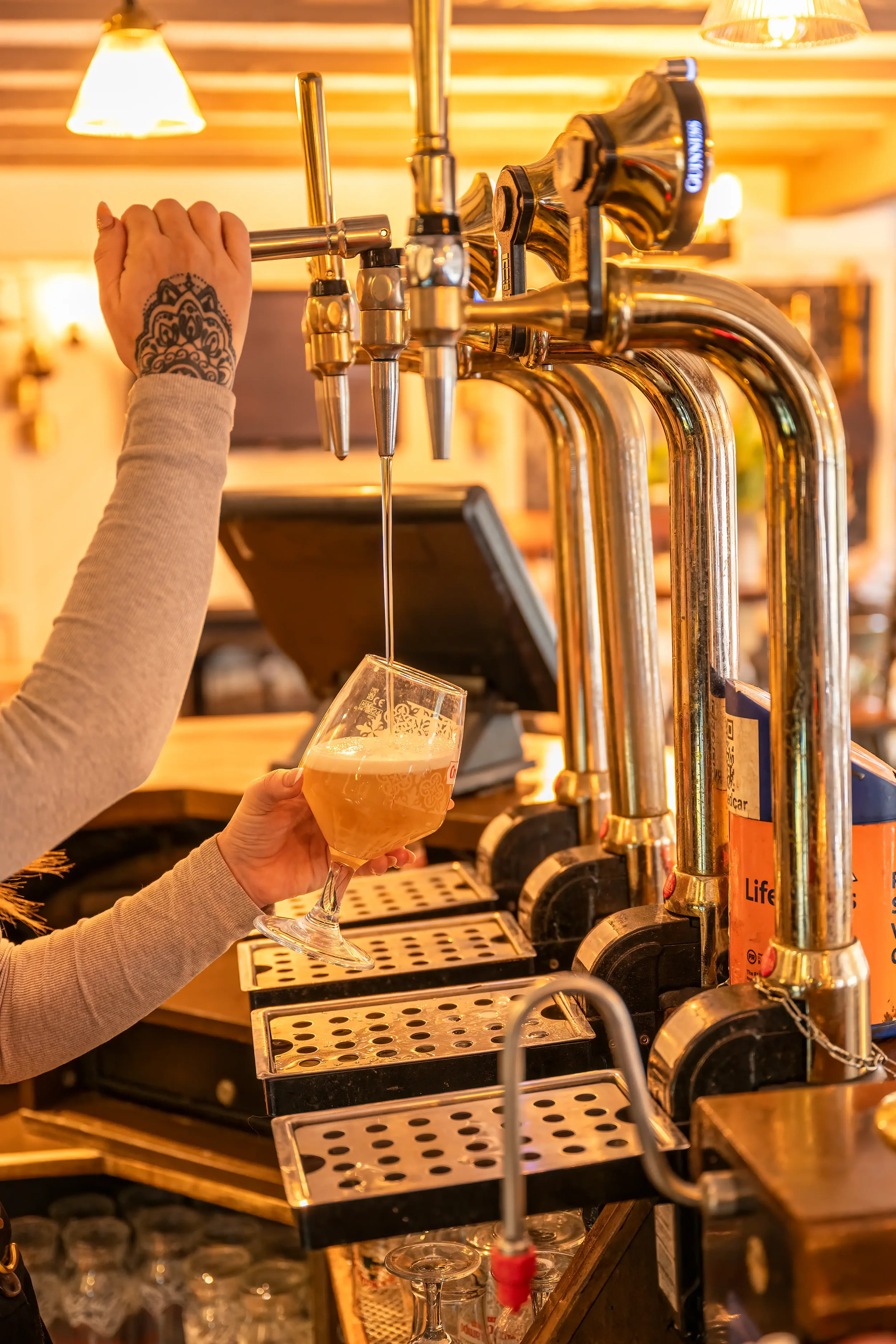 Colour photograph of a pint of lager being served at the bar in a country pub