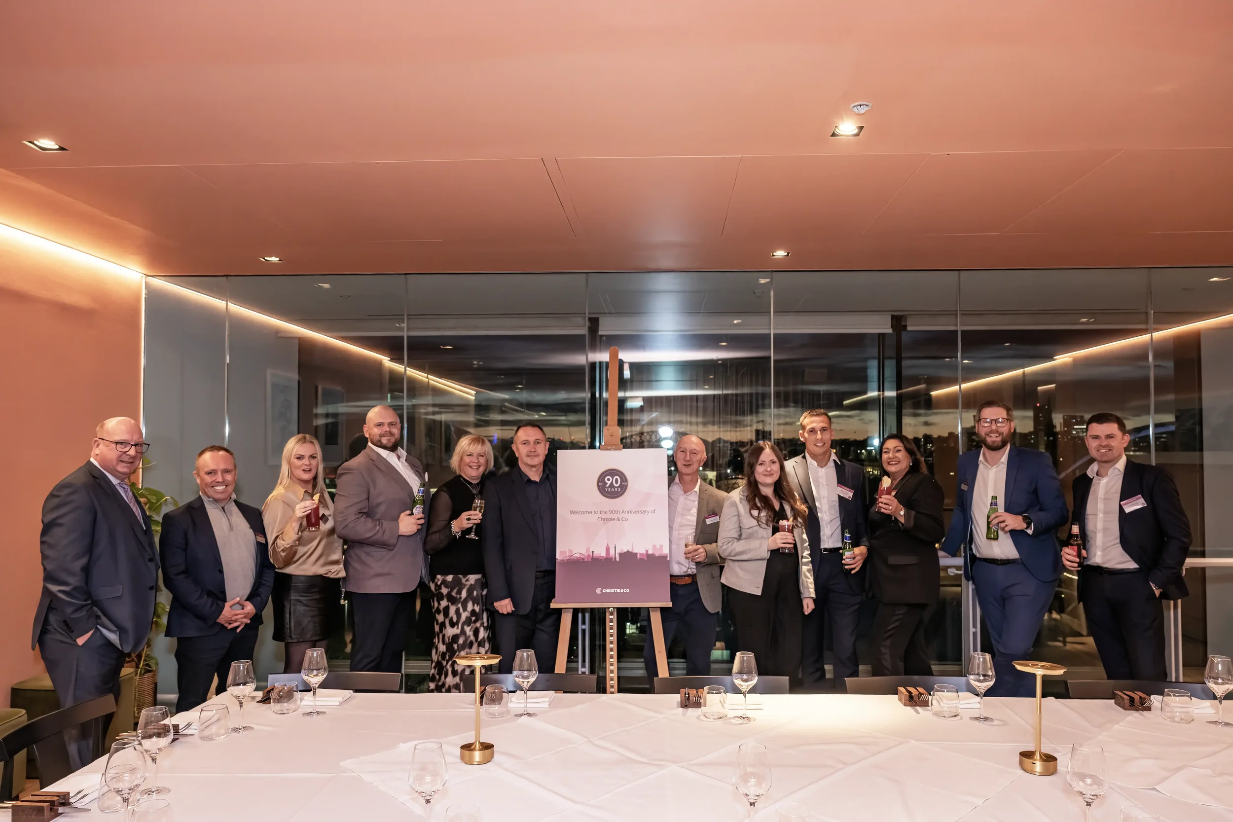 Colour photograph of a group of team members at a corporate event, with event banner in the middle