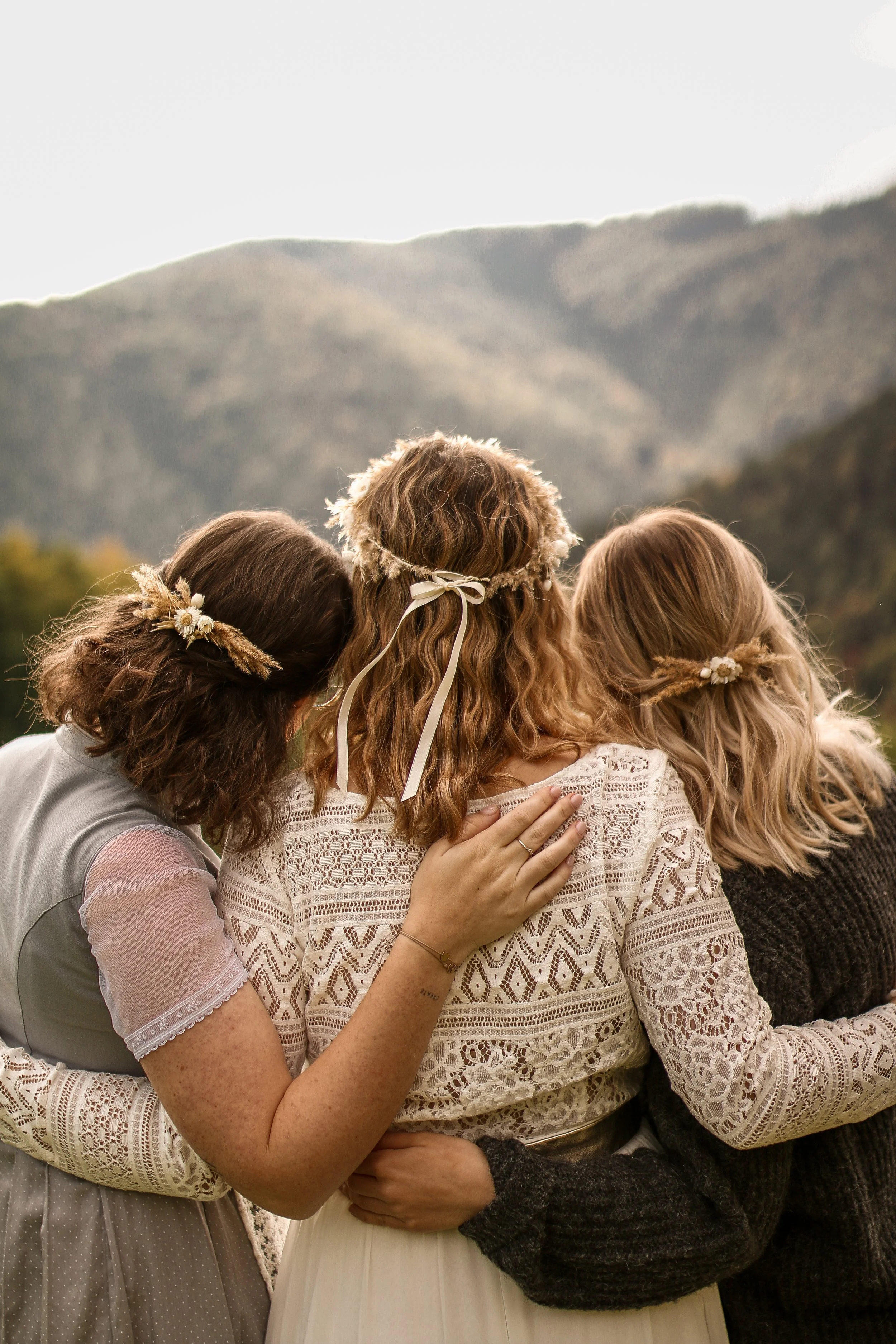 Freundinnengruppe steht Arm in Arm mit der Braut und blickt in die Ferne – natürlich und emotional.