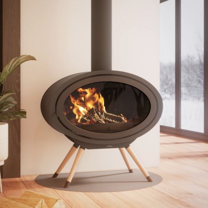 Modern oval-shaped fireplace with visible flames, positioned in a cozy living room near large floor-to-ceiling windows and a potted plant.