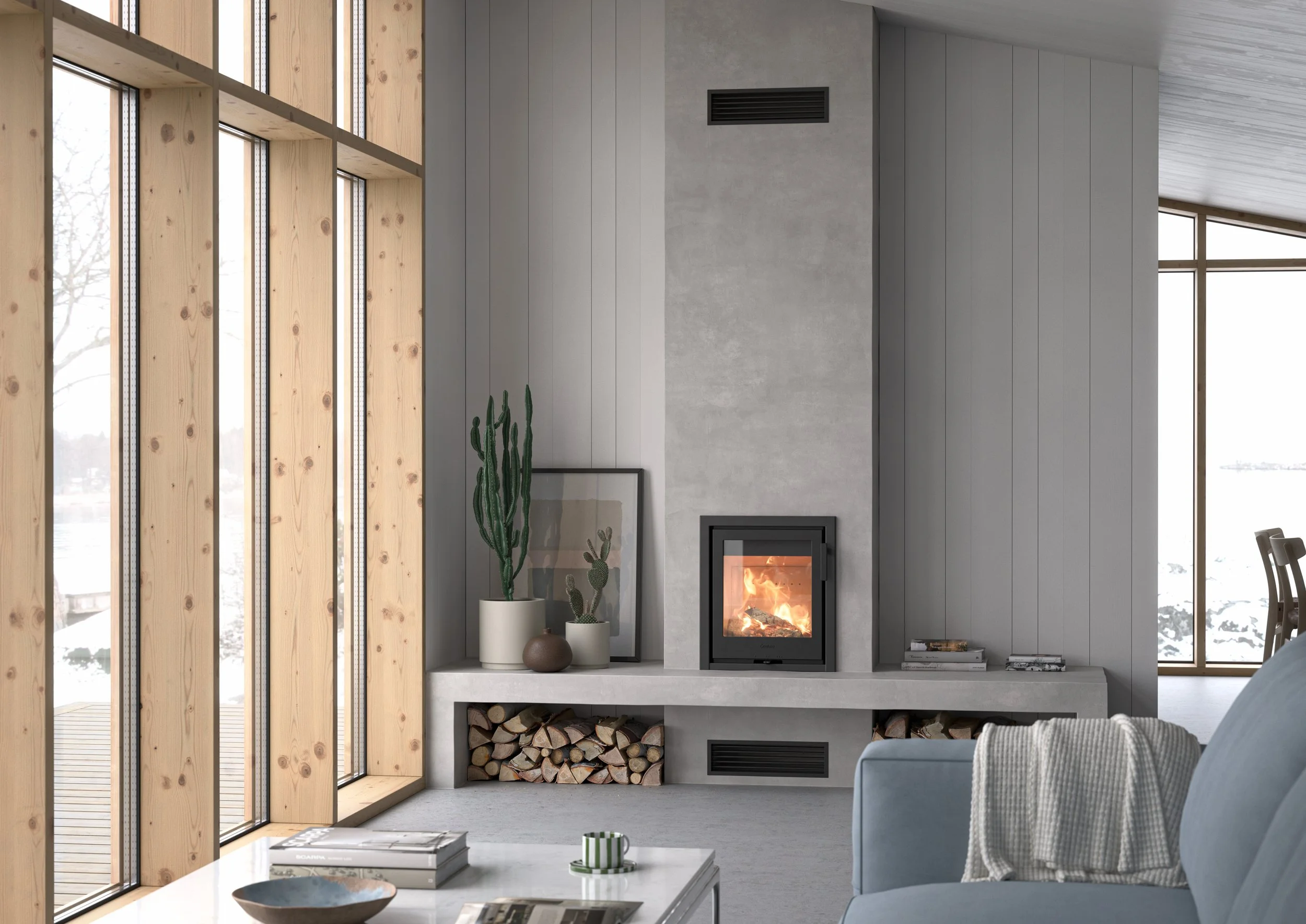 Modern living room with large windows, a wood fireplace with fire burning, and a stack of firewood underneath. There are decorative vases with cacti on the mantel, a framed picture, and a striped mug on the coffee table.