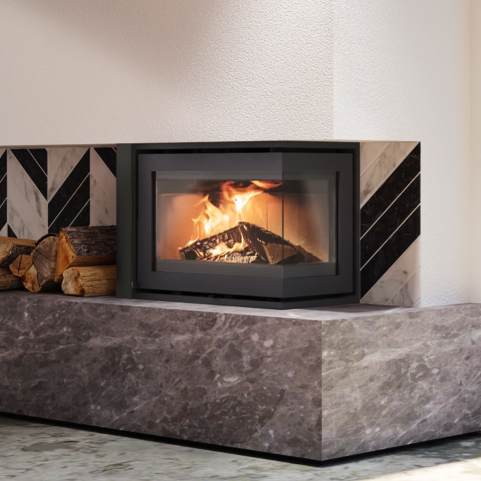 A lit fireplace with fire burning inside, set into a stone and tile wall with logs nearby.
