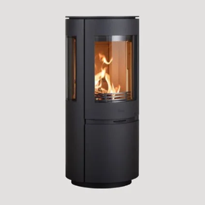 A modern black wood stove with a glass front showing a lit fire inside.
