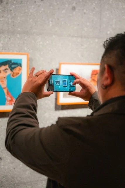 Person taking a photo of artwork at an art gallery with a smartphone.