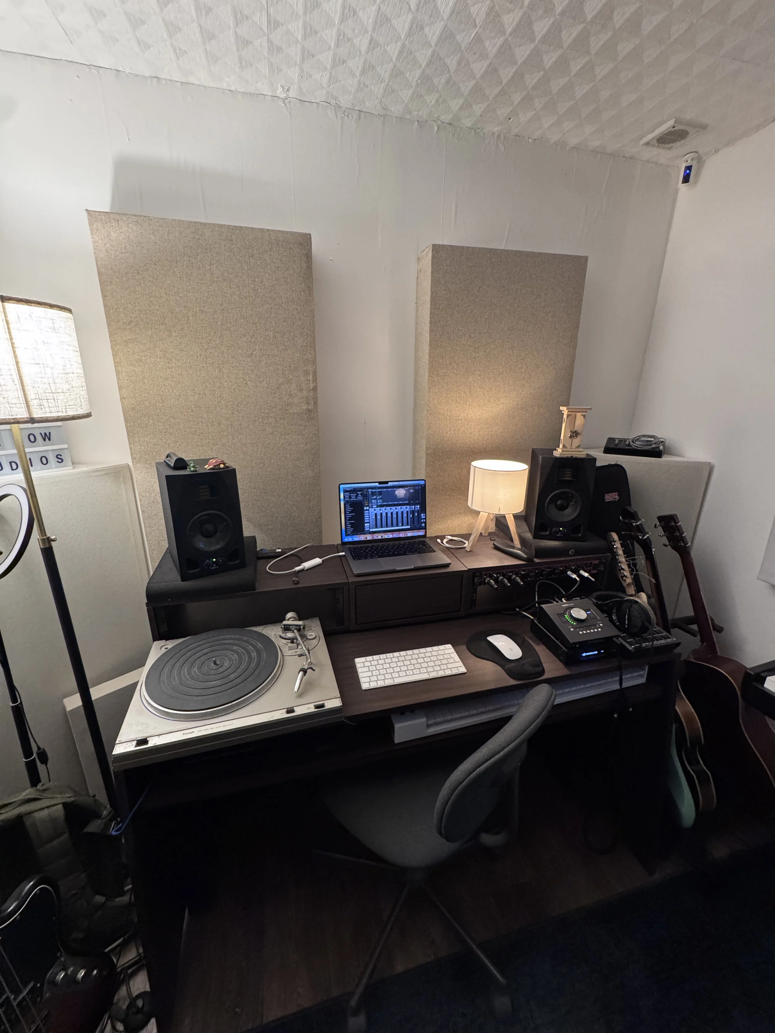 Music production workstation at The Low Studios with monitors, instruments, and acoustic treatment.