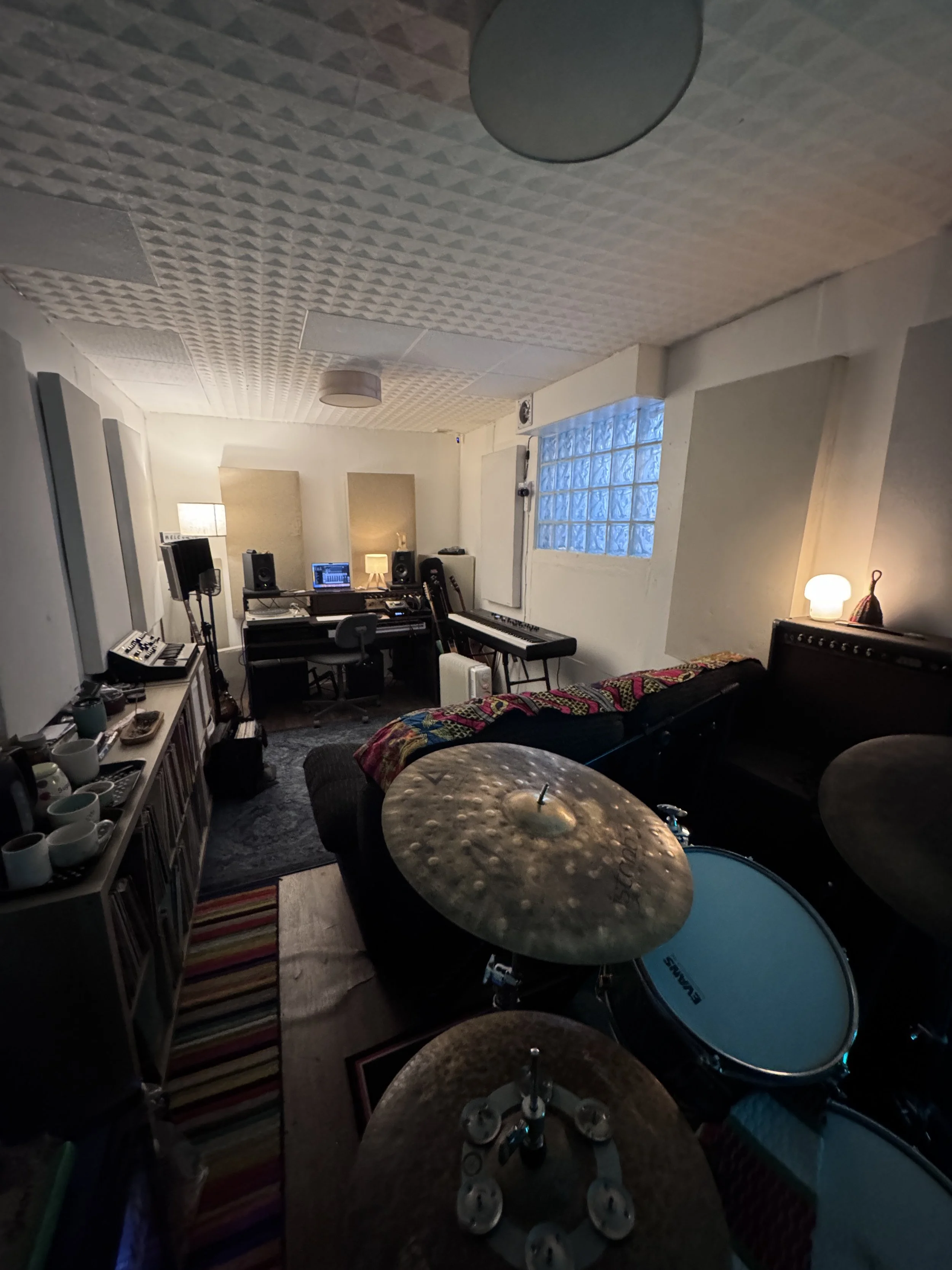 Recording room at The Low Studios featuring drum kit, instruments, and relaxed seating area.