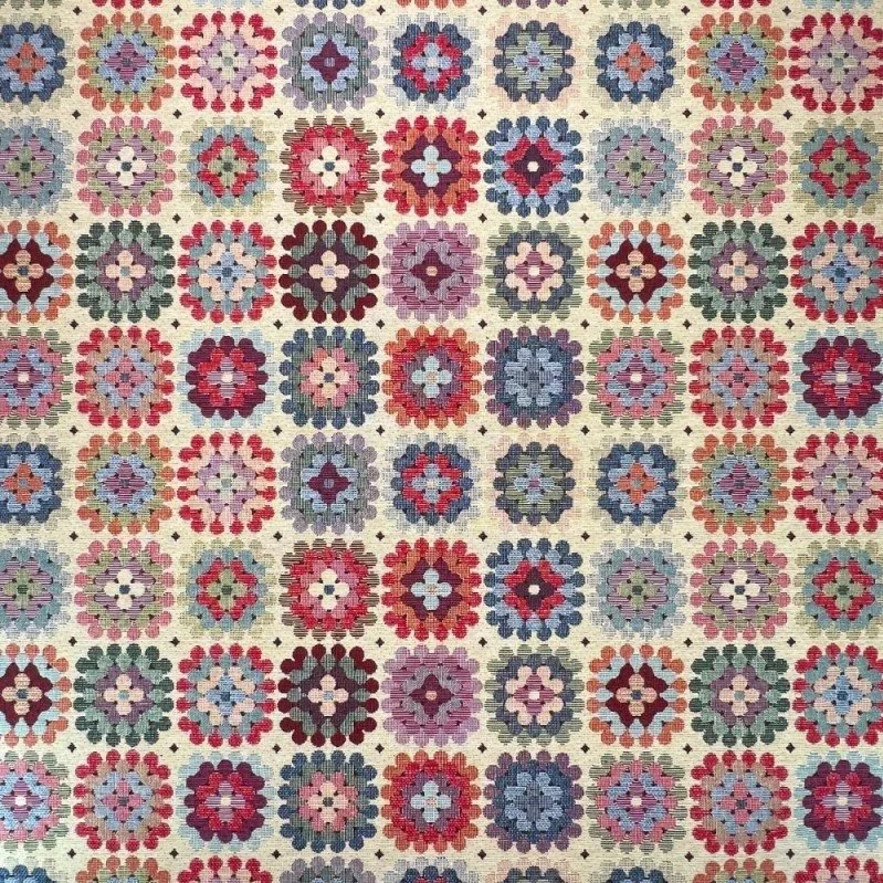 Close-up of a colorful quilt with a repeating pattern of circular floral motifs in pink, purple, red, blue, and green on a cream background.
