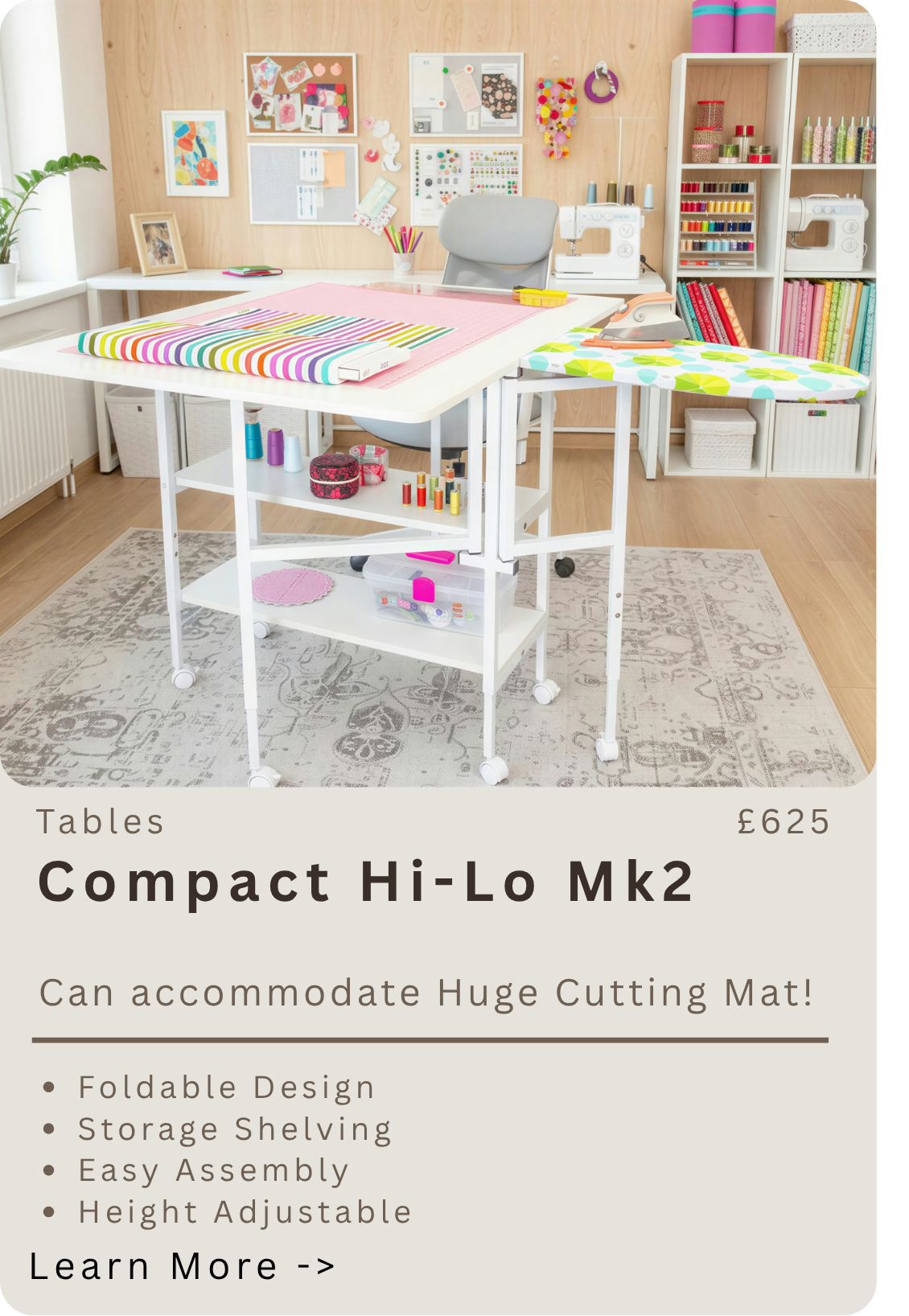 A bright sewing and craft workspace with a white foldable table, an iron, and a sewing machine on a desk. The room features wooden walls, shelves with sewing supplies, colorful fabric, and decorative wall art.